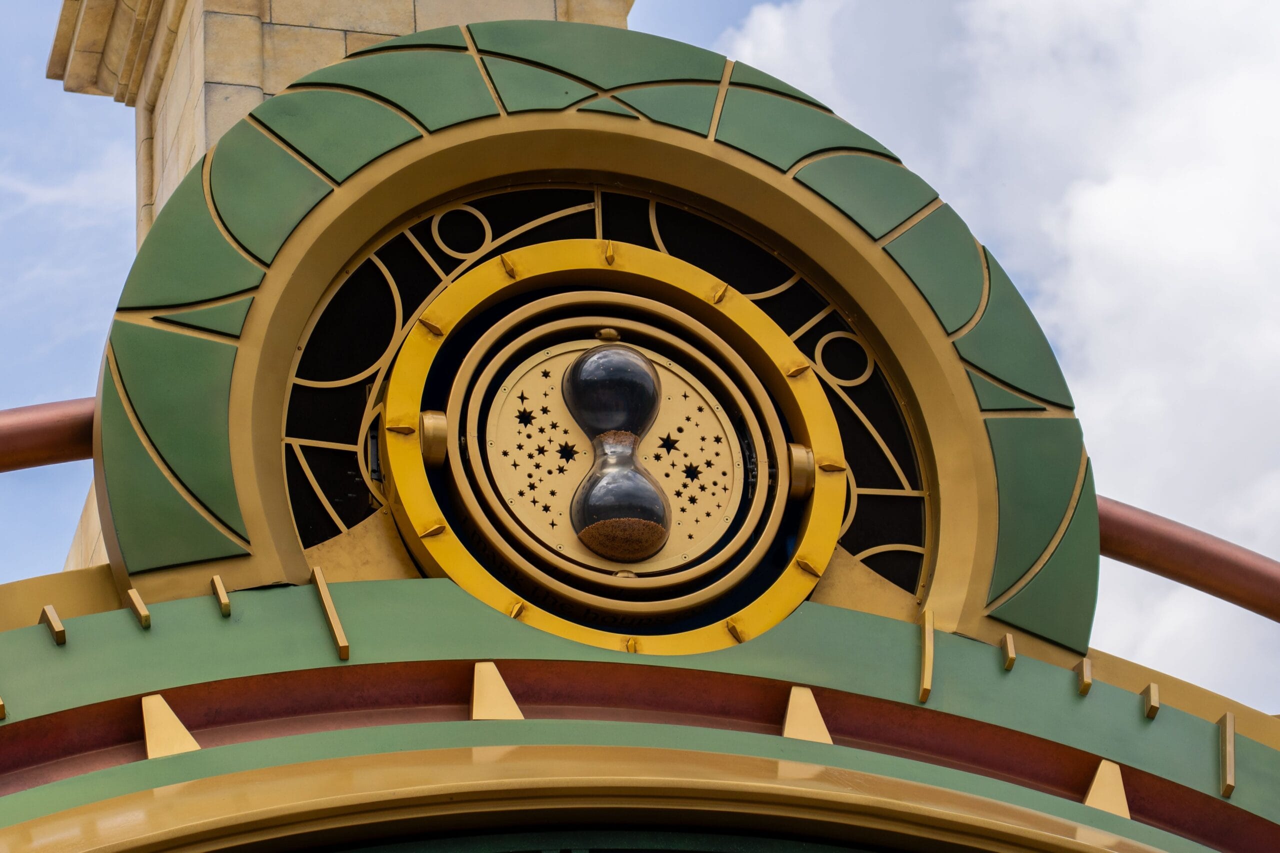 Art deco clock with hourglass center, in green and gold, echoing the grandeur of Disney park icons like Cinderella Castle.