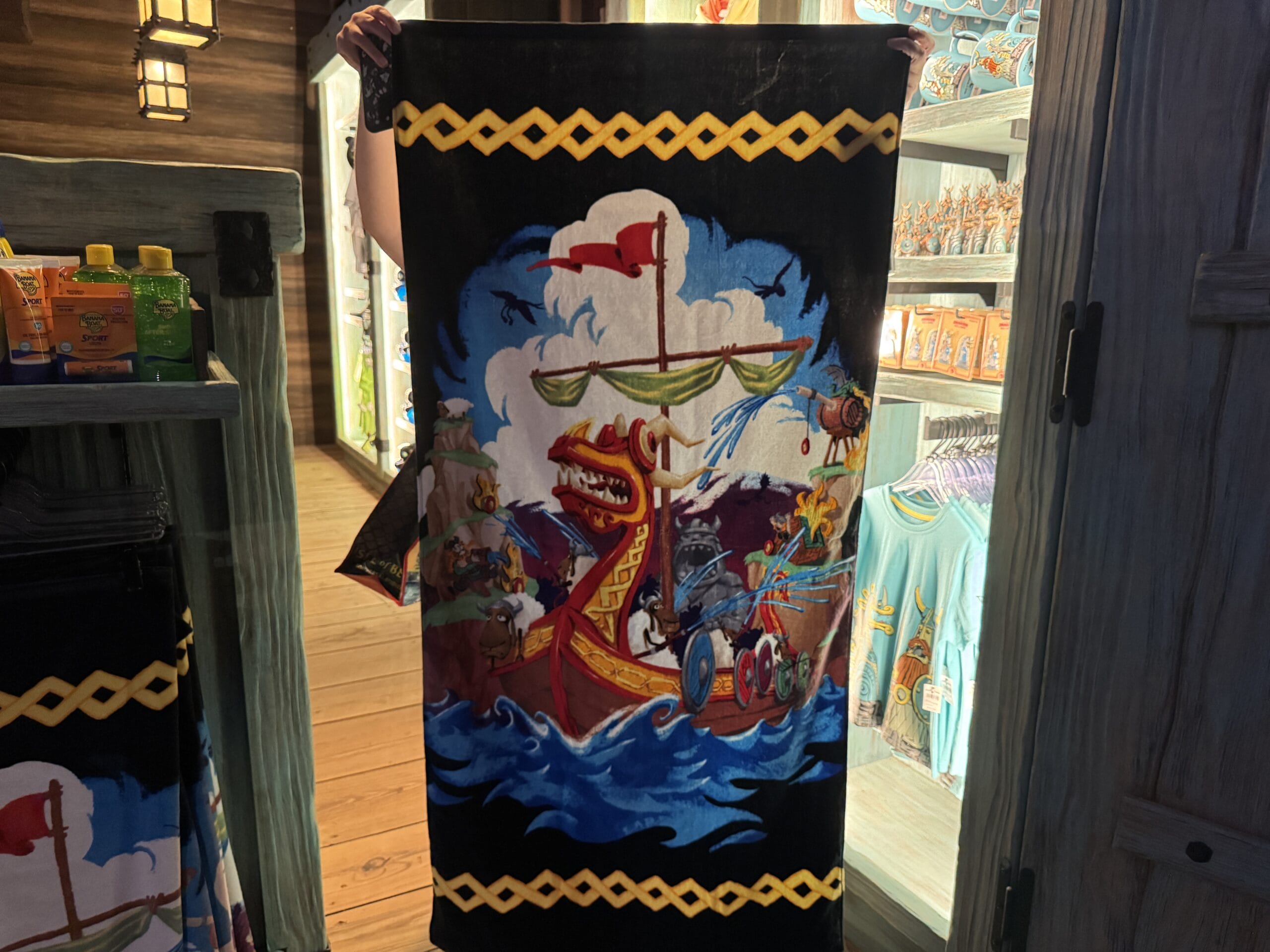 A Spit Fyre towel shows a cartoon Viking ship with a dragon head—unlike any Disney castle, but fun park merch for fans.