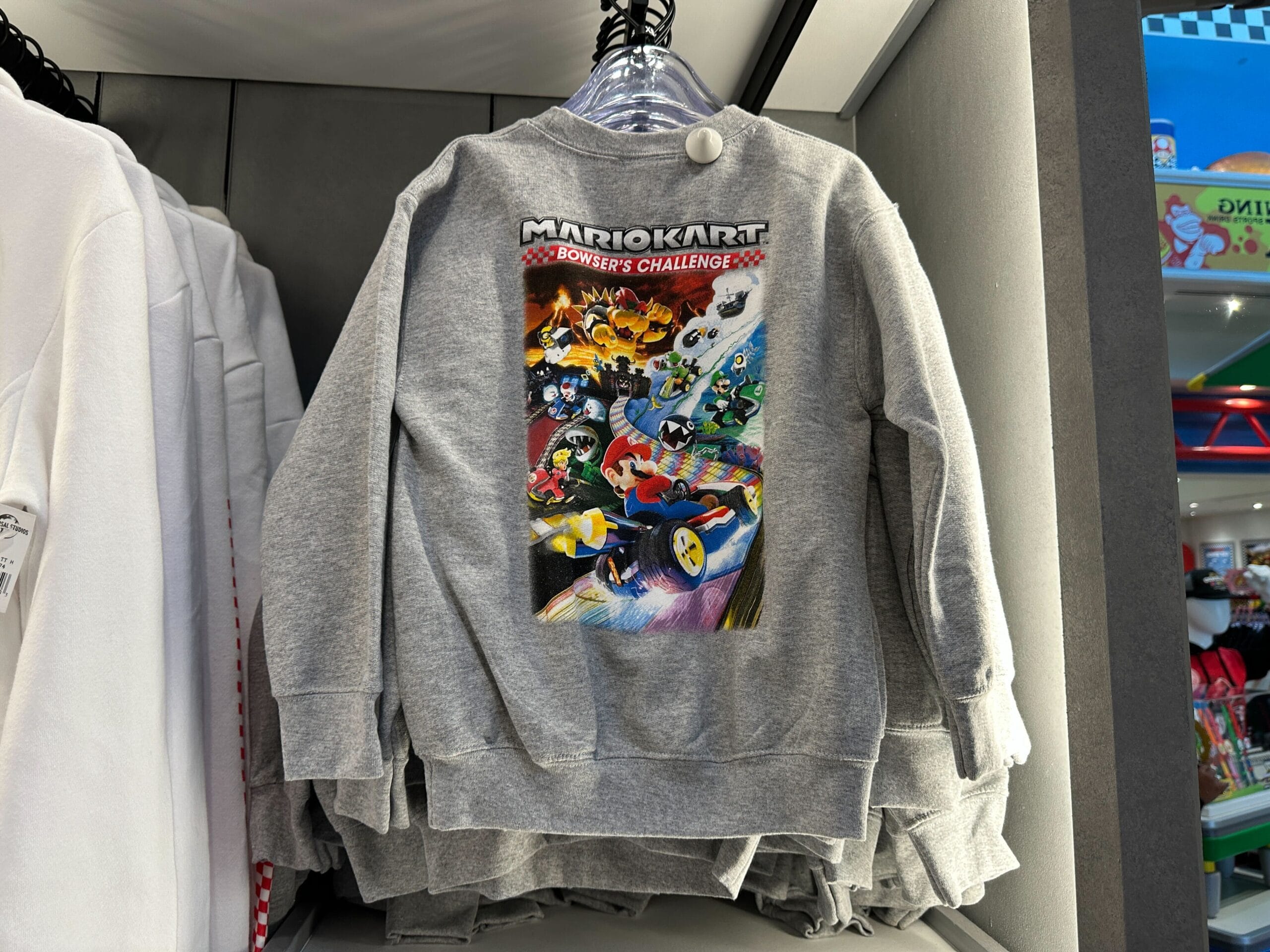 A gray sweatshirt with a vibrant Mario Kart: Bowser’s Challenge design, great for theme parks—though not Disney castle merch.