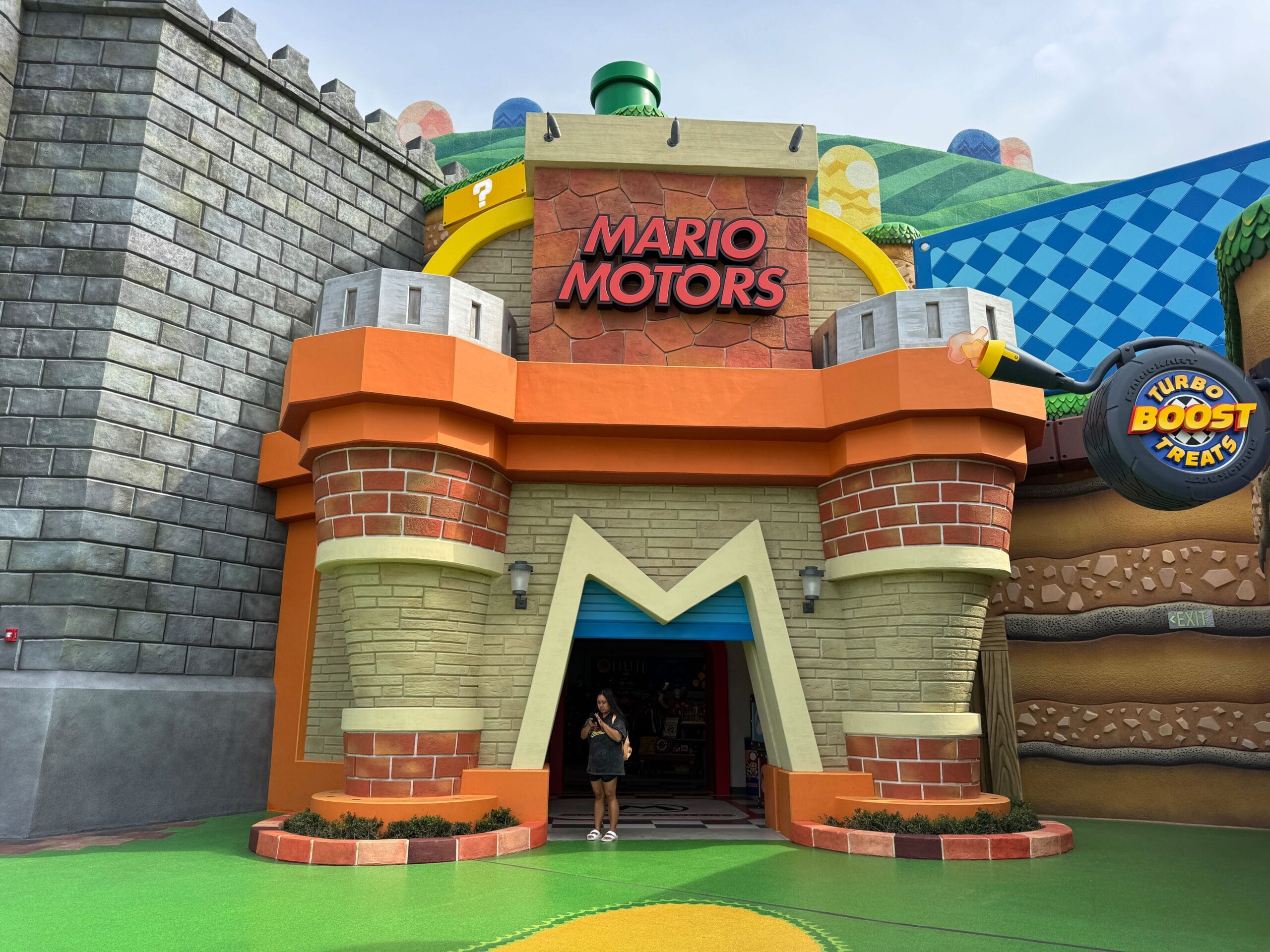 Vibrant Mario Motors entrance at Super Nintendo World, resembling a whimsical theme park like Disney, with a person in the doorway.