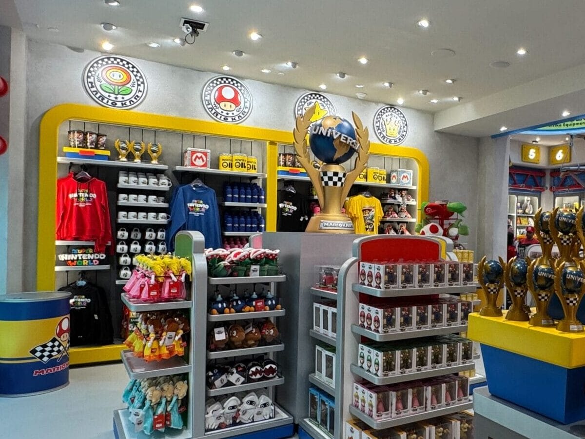 Vibrant shop with Mario Motors toys, plushies, T-shirts, and themed merch—distinct from Disney Parks’ castle gift shops.