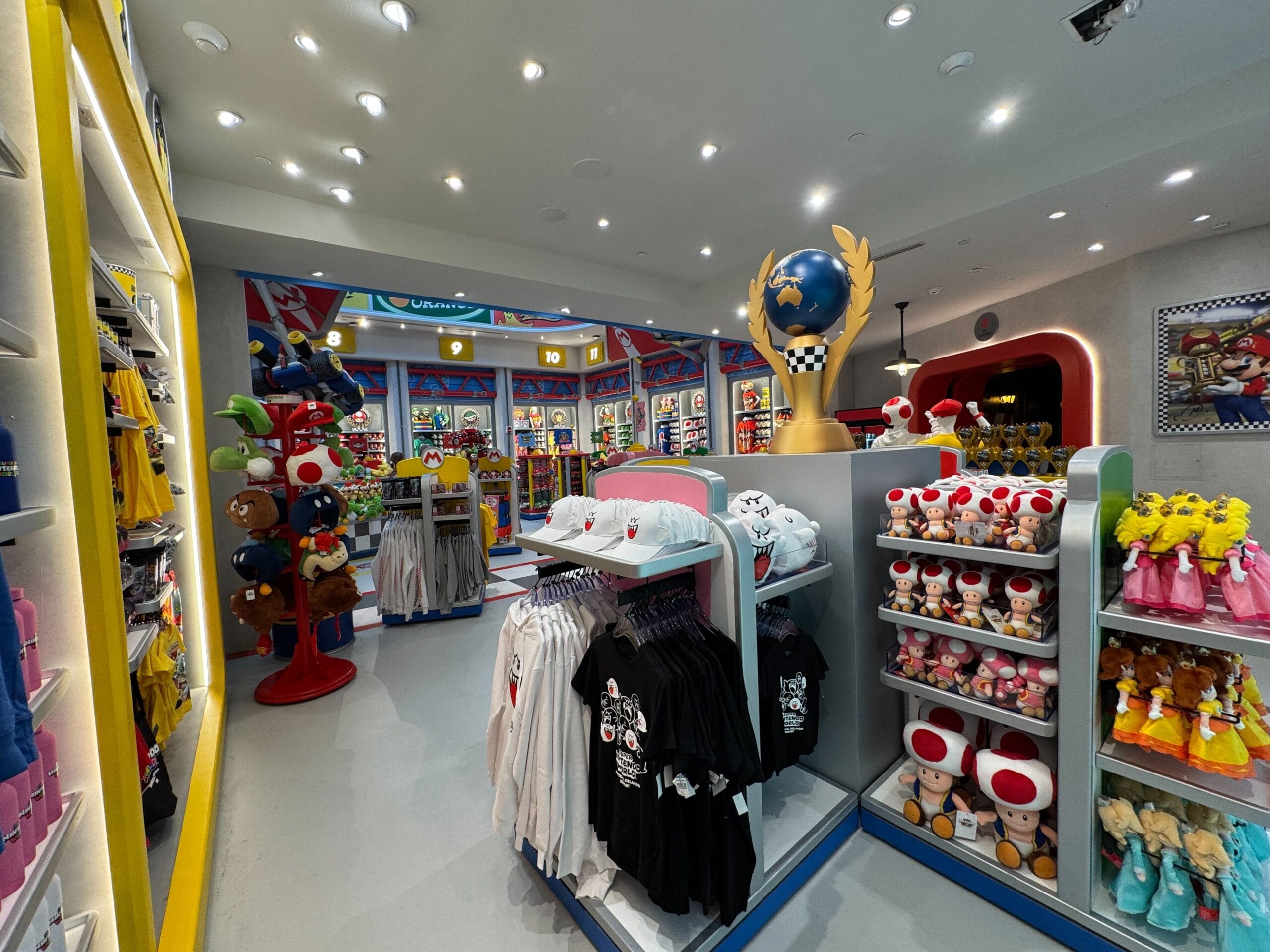 Colorful shop brimming with Super Mario-themed merchandise and plush toys, reminiscent of Disney gift shops but Nintendo-themed.