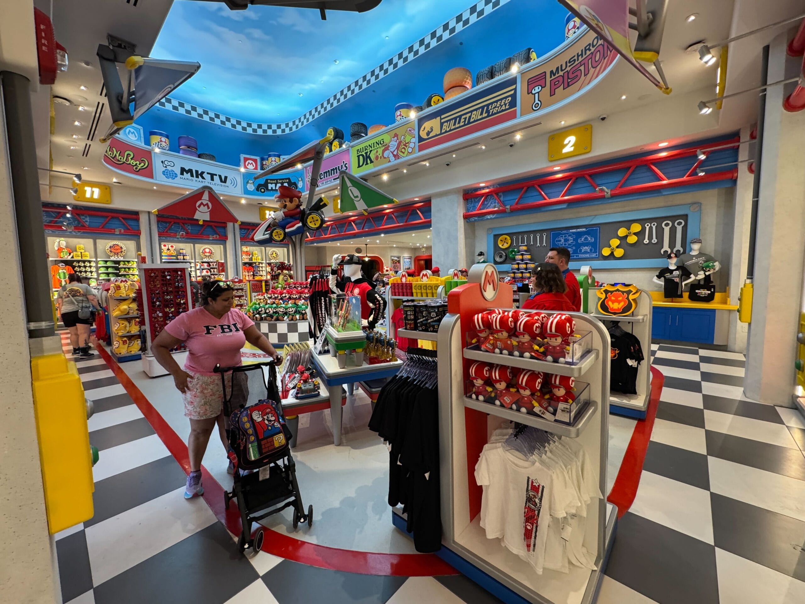 A vibrant Super Mario-themed shop in Epic Universe displays toys, shirts, and Mario Motors items—unlike Disney parks’ castle shops.