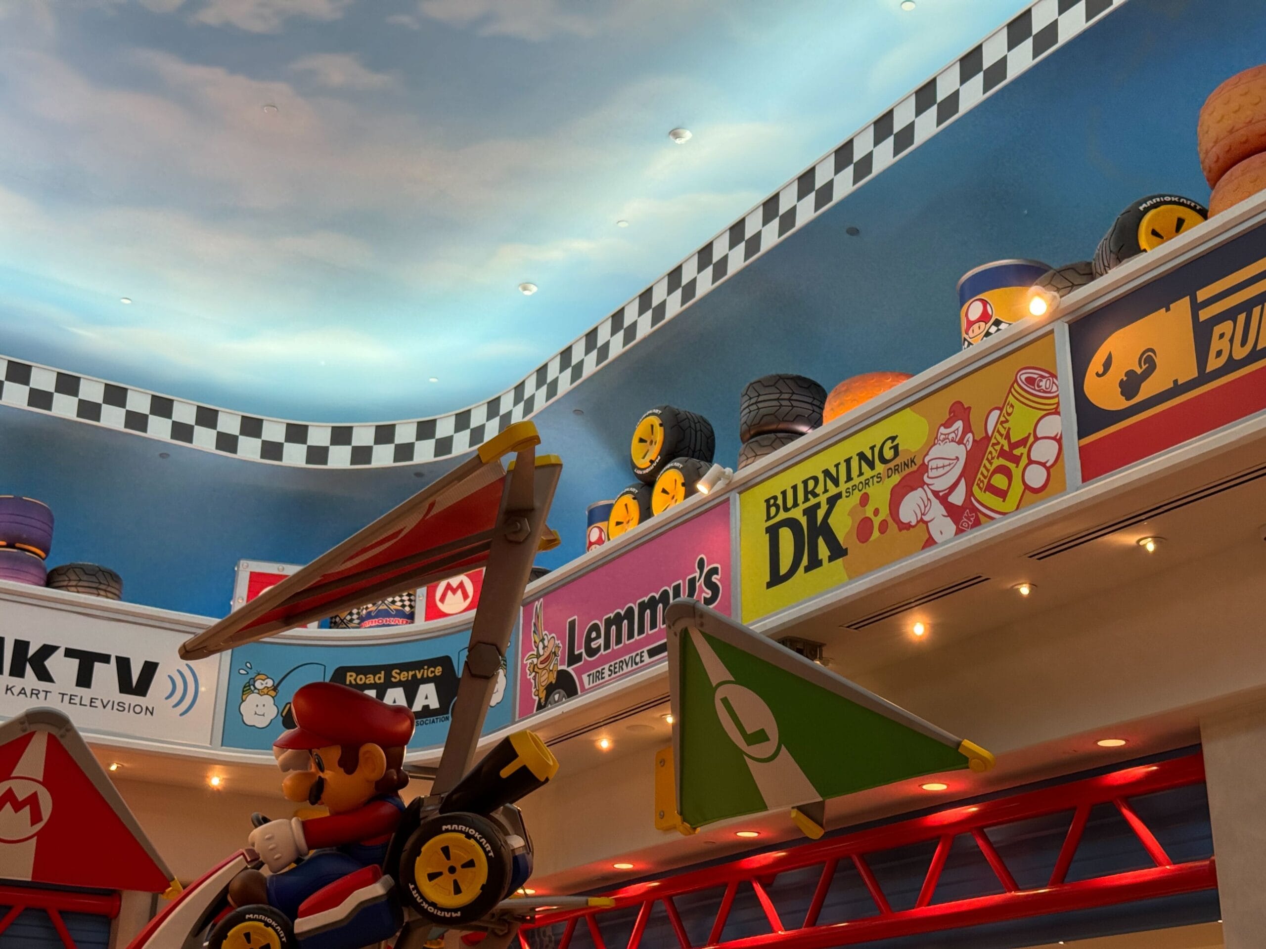 Indoor Mario Motors area in Epic Universe, featuring a Mario glider, vibrant signs, tires, and character faces—no Disney castle seen.