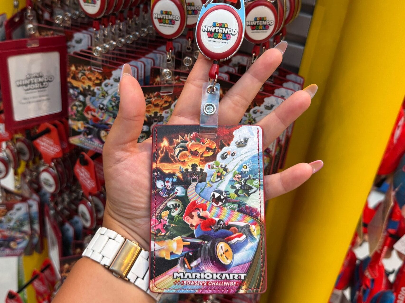 Hand holding a Mario Motors pass holder at Super Nintendo World display in Epic Universe, not featuring any Disney castle comparison.