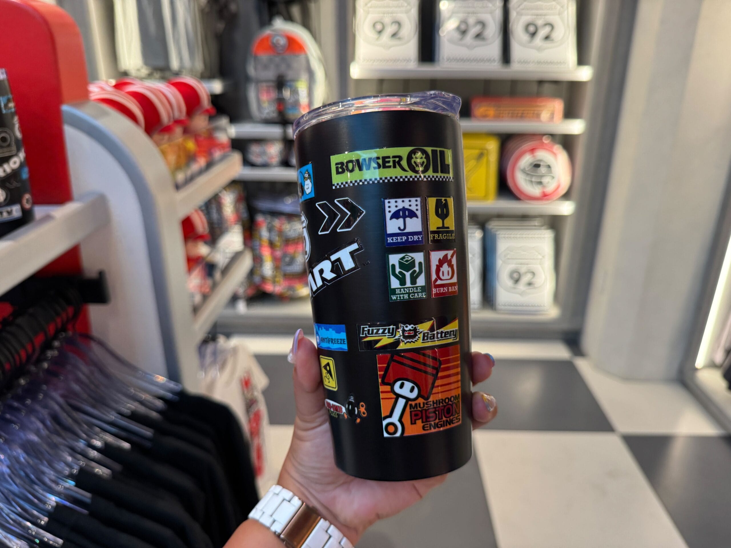A hand holds a Mario Kart-themed tumbler, similar to the fun drinkware found in Disney Parks, though not featuring any Disney castles.