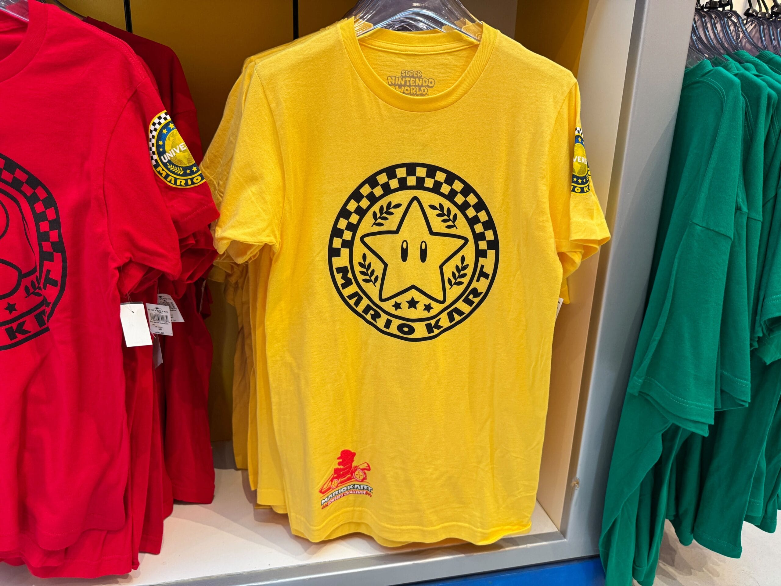 Yellow Mario Kart T-shirt with a star and checkered circle, similar in spirit to themed tees at Disney parks but from Super Nintendo World.