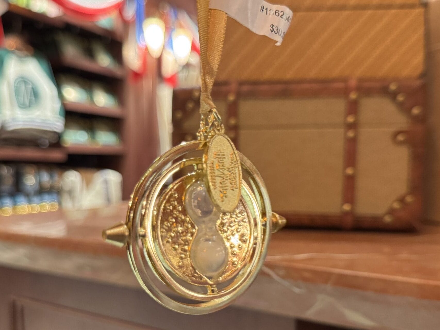 A gold time turner ornament hangs in a store filled with Wizarding World of Harry Potter merchandise.