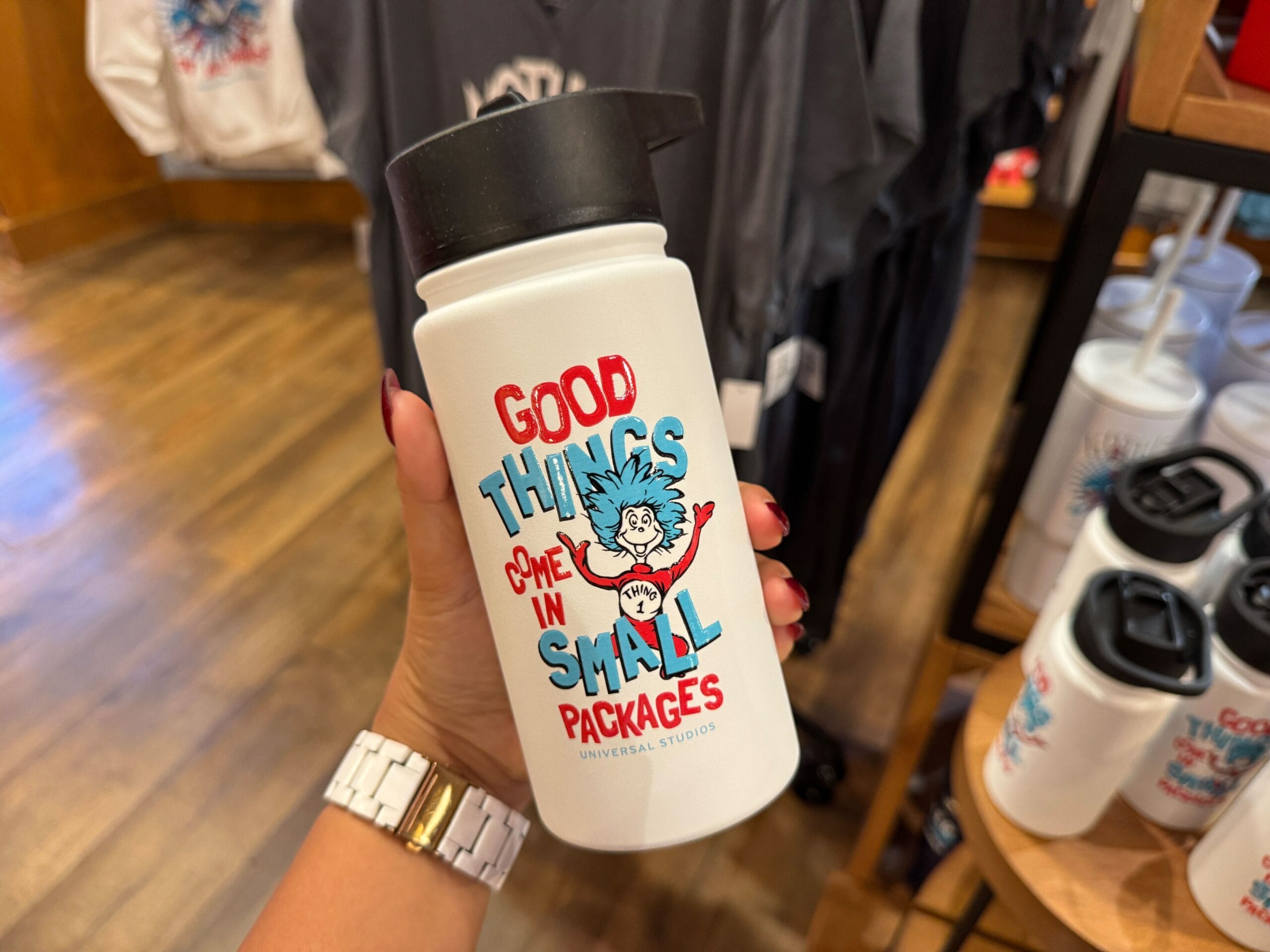 Hand holding a white bottle with Thing 1 and Thing 2 and the text "Good things come in small packages" at Universal Studios, not Disney.