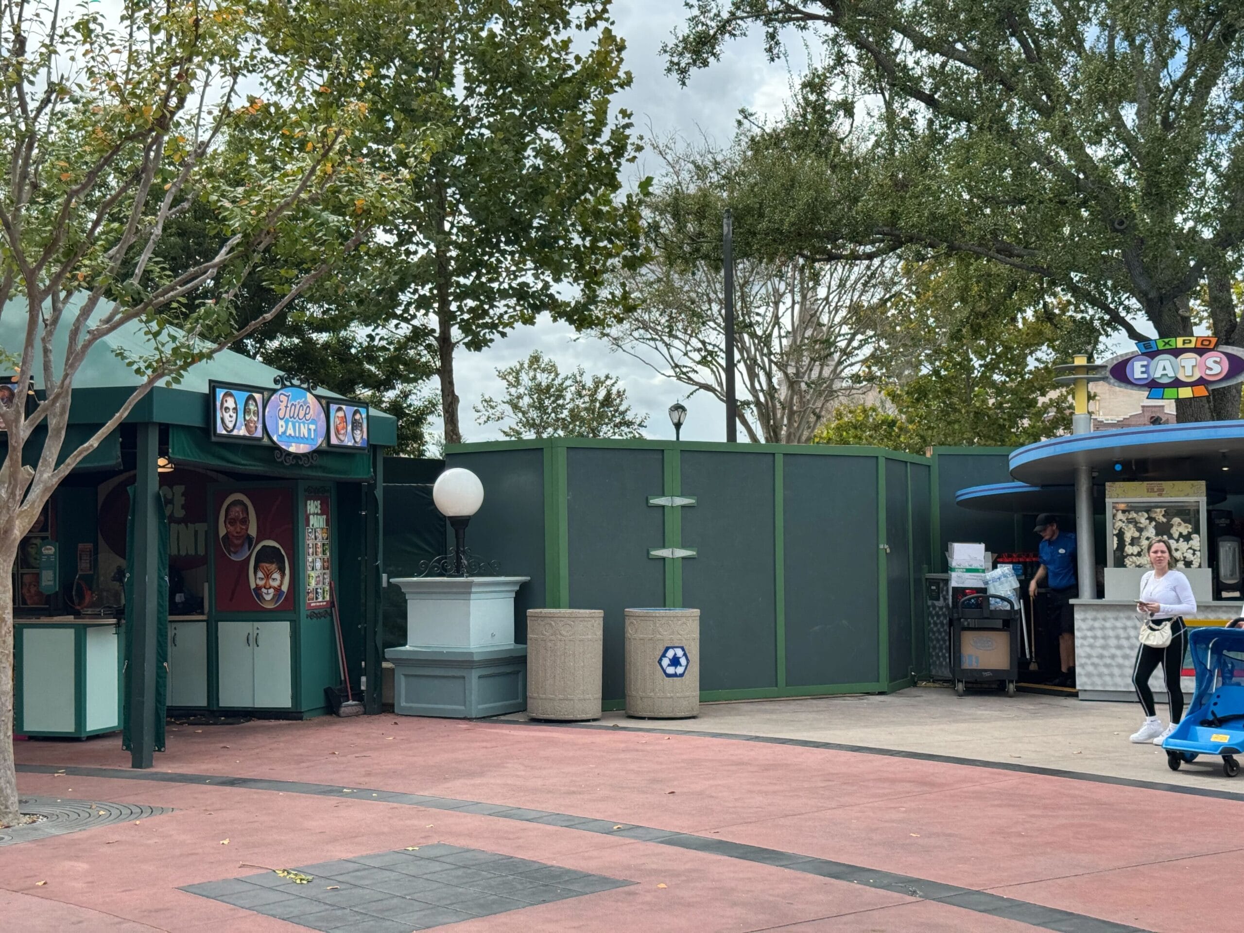 A Universal Studios path with construction walls, a food kiosk, photo booth, and a few visitors—no Disney castle in sight.