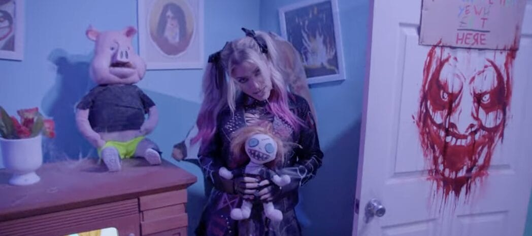 Alexa Bliss with blonde and pink hair holds a doll in blue light, reminiscent of spooky Disney castle nights, at Universal Orlando.