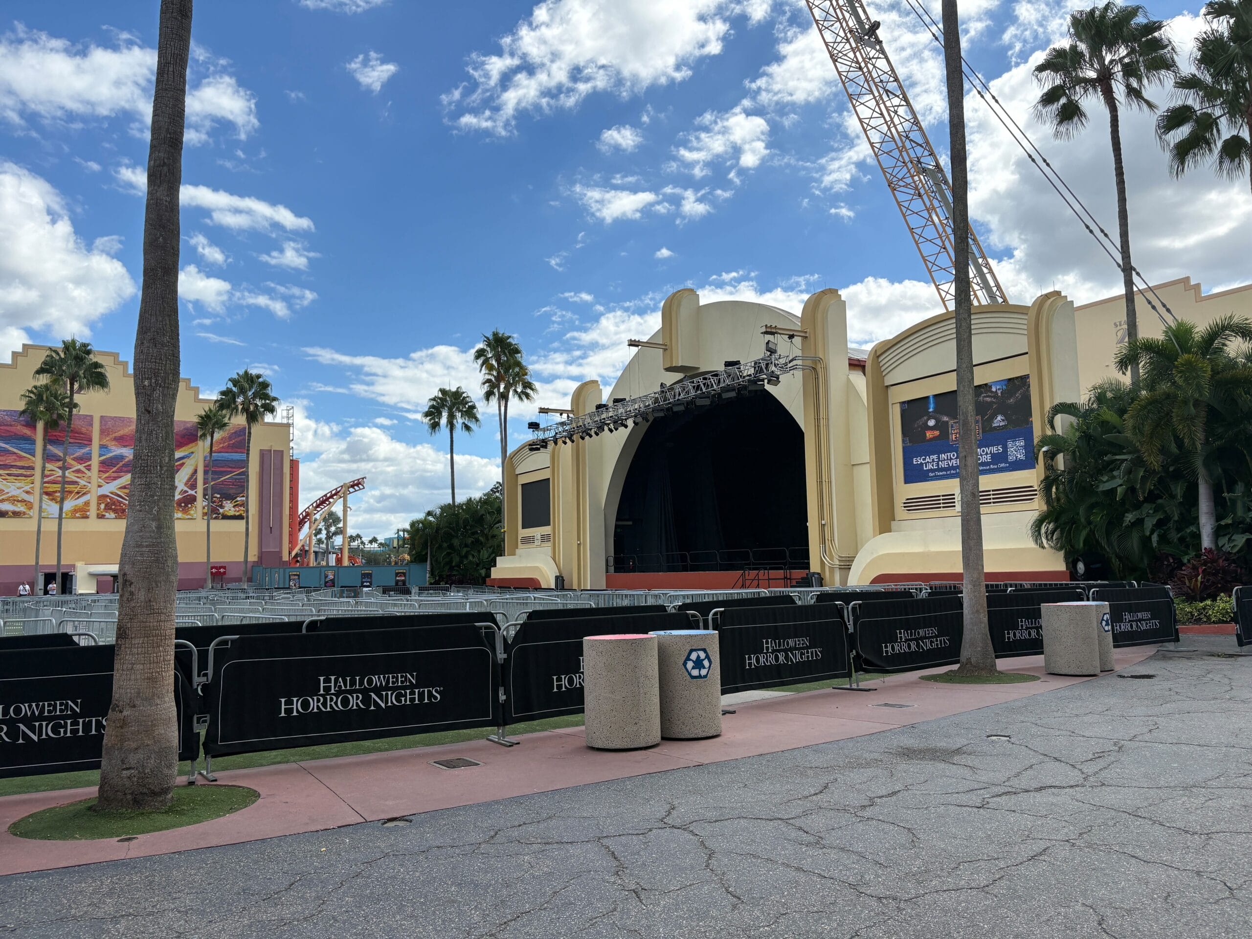 Outdoor stage at Universal Studios Orlando with Halloween Horror Nights barriers. A crane towers overhead from the Hollywood Rip Ride Rockit demolition site, seen off to the left.