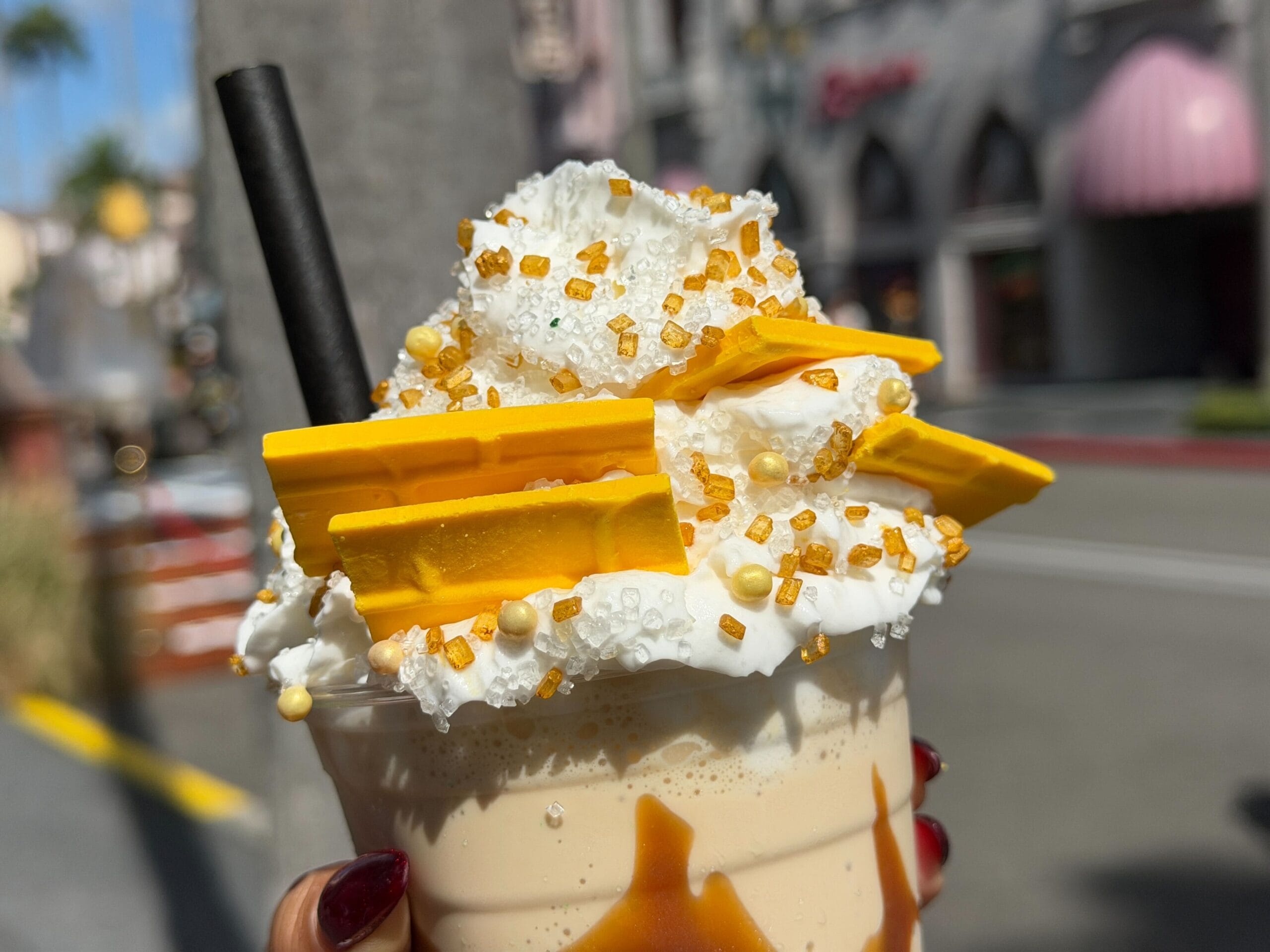 A close-up of a caramel milkshake topped with whipped cream and sprinkles, enjoyed at a theme park outside Disney Parks.