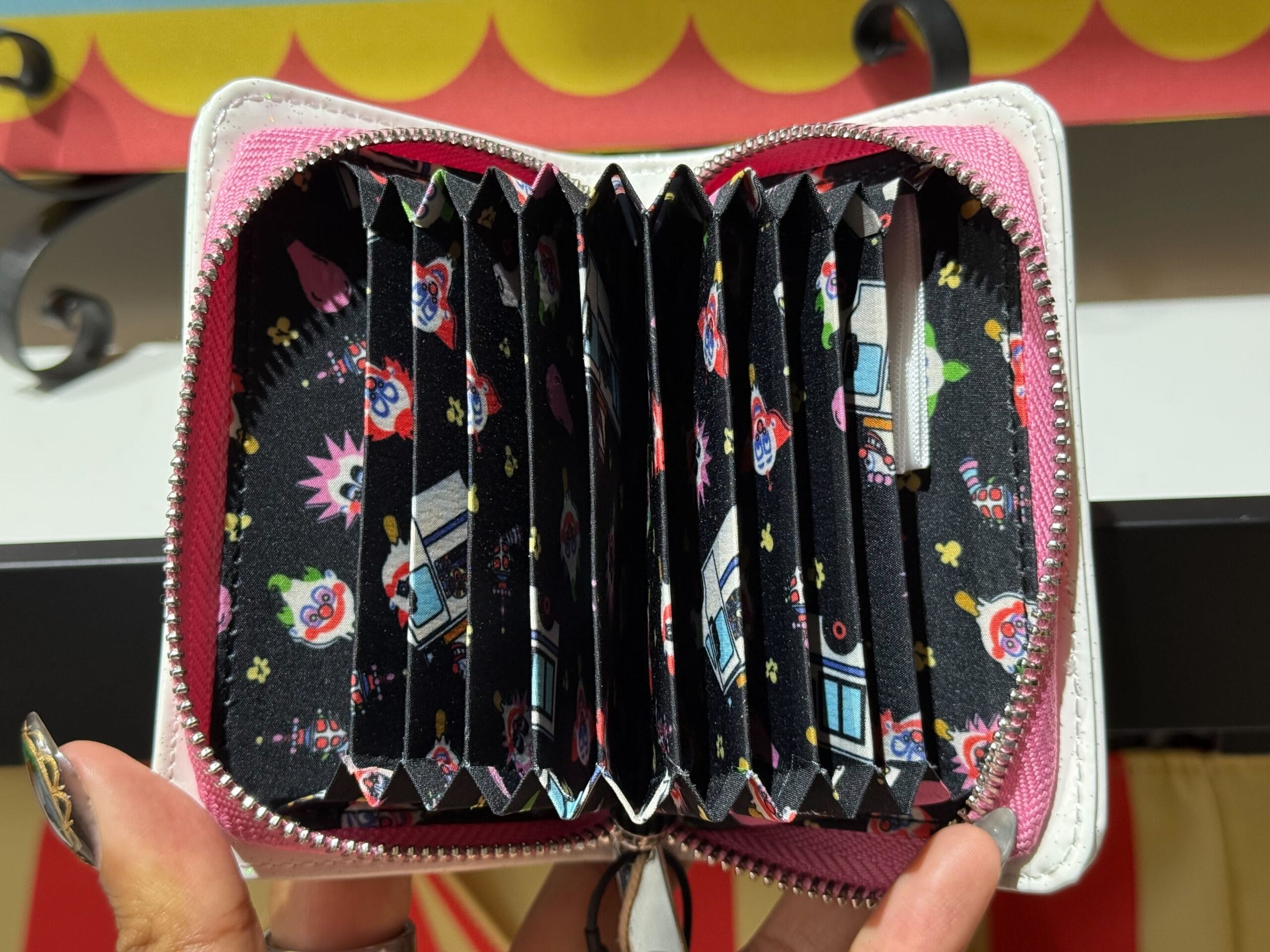 Open pink accordion wallet with black interior and "Killer Klowns from Outer Space" pattern.