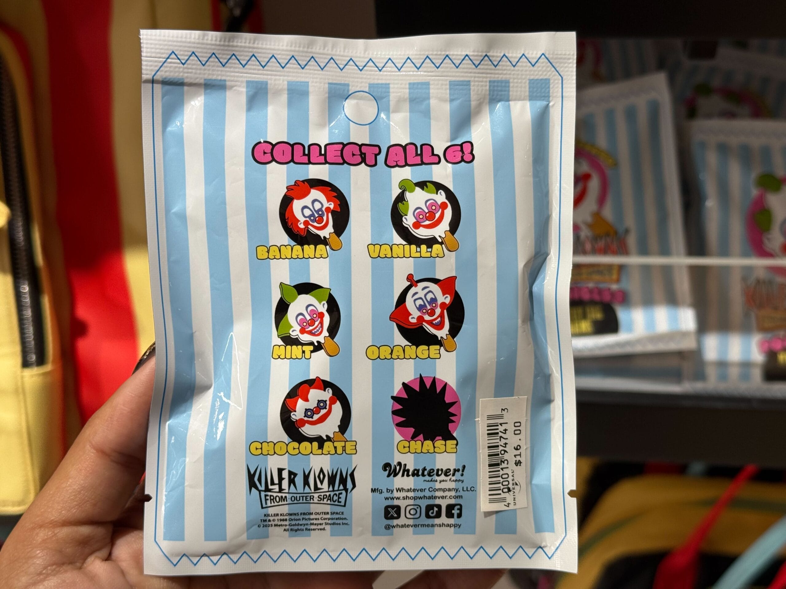 A hand shows a "Killer Klowns from Outer Space" popsicle mystery bag charm pouch at Universal Studios.