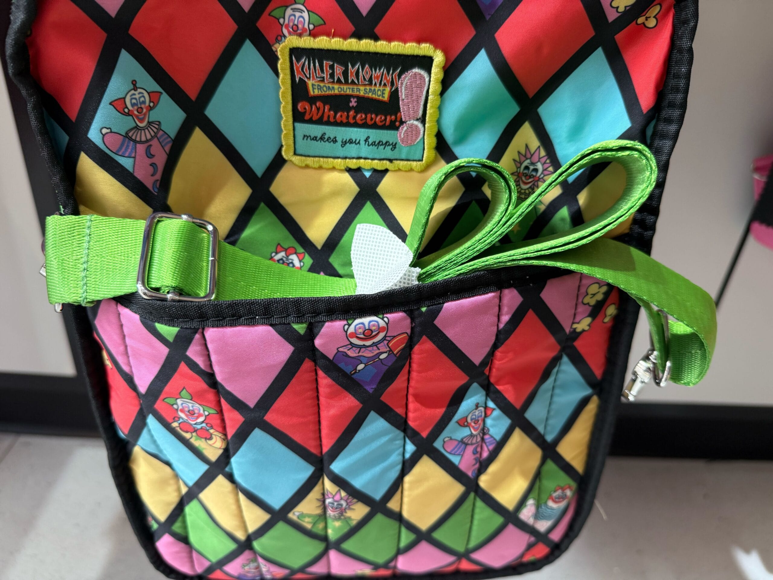 A vibrant quilted bag with clown faces, a green strap, and a Killer Klowns from Outer Space patch.