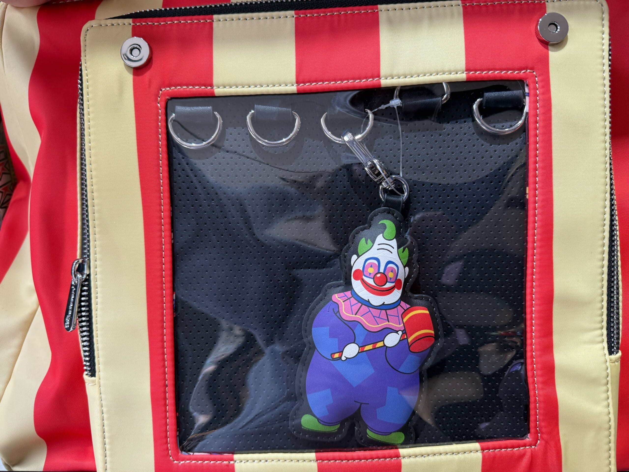 Red and beige striped circus tent bag with clown keychain, Killer Klowns from Outer Space merch.