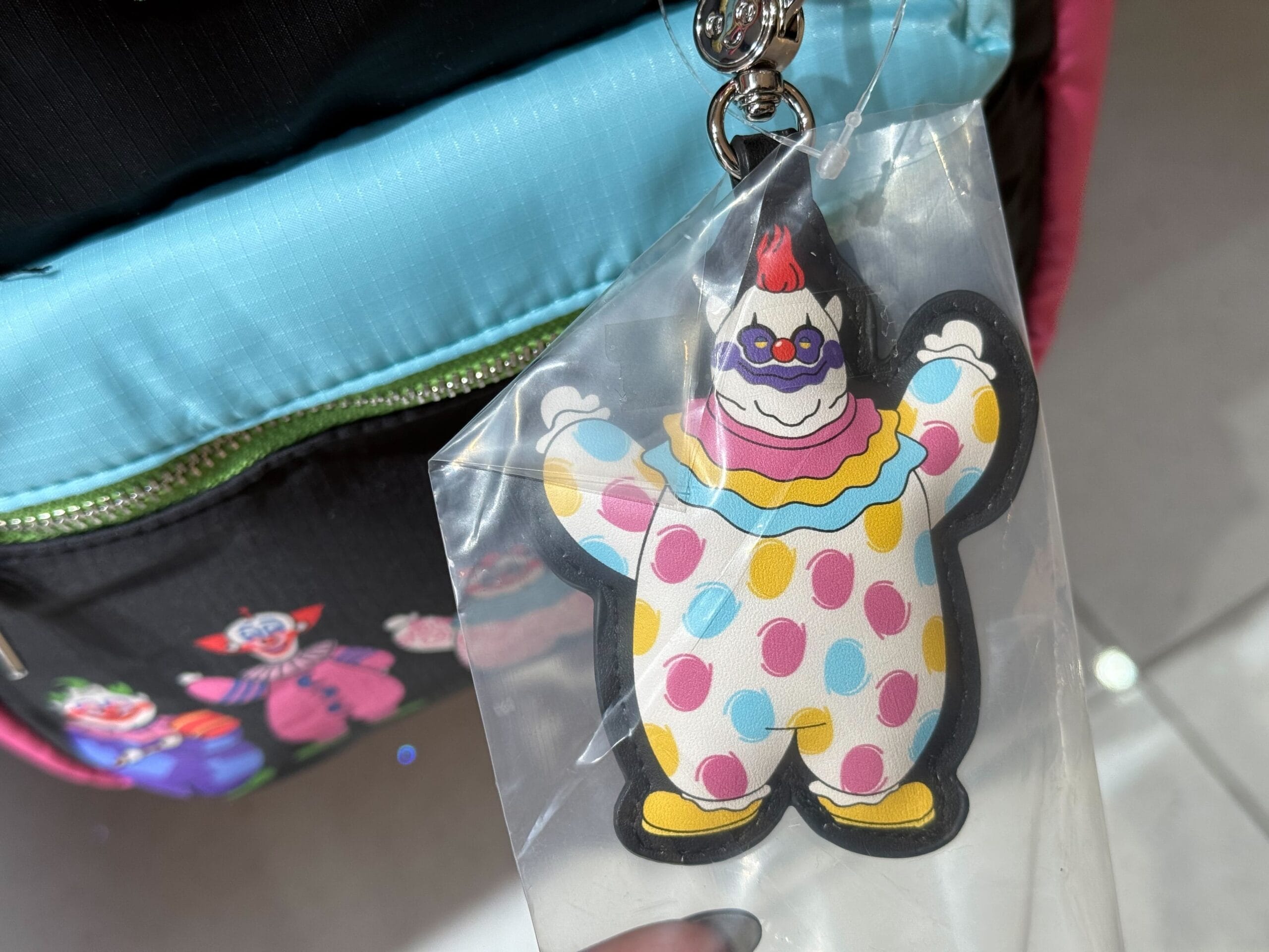 A vibrant clown keychain hangs on a backpack with playful clown patterns.
