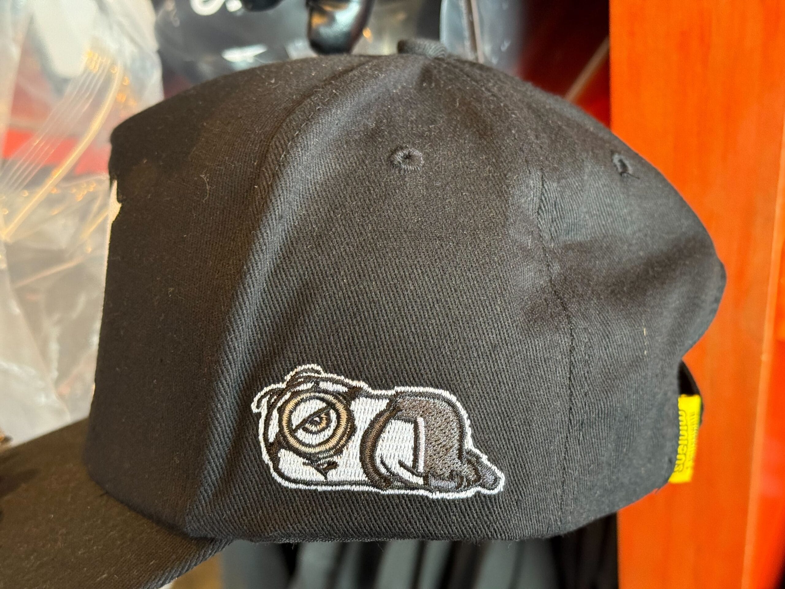 A black cap with an embroidered patch of an Emo Minion lying down—not Disney like iconic castle hats from Disneyland or Magic Kingdom.