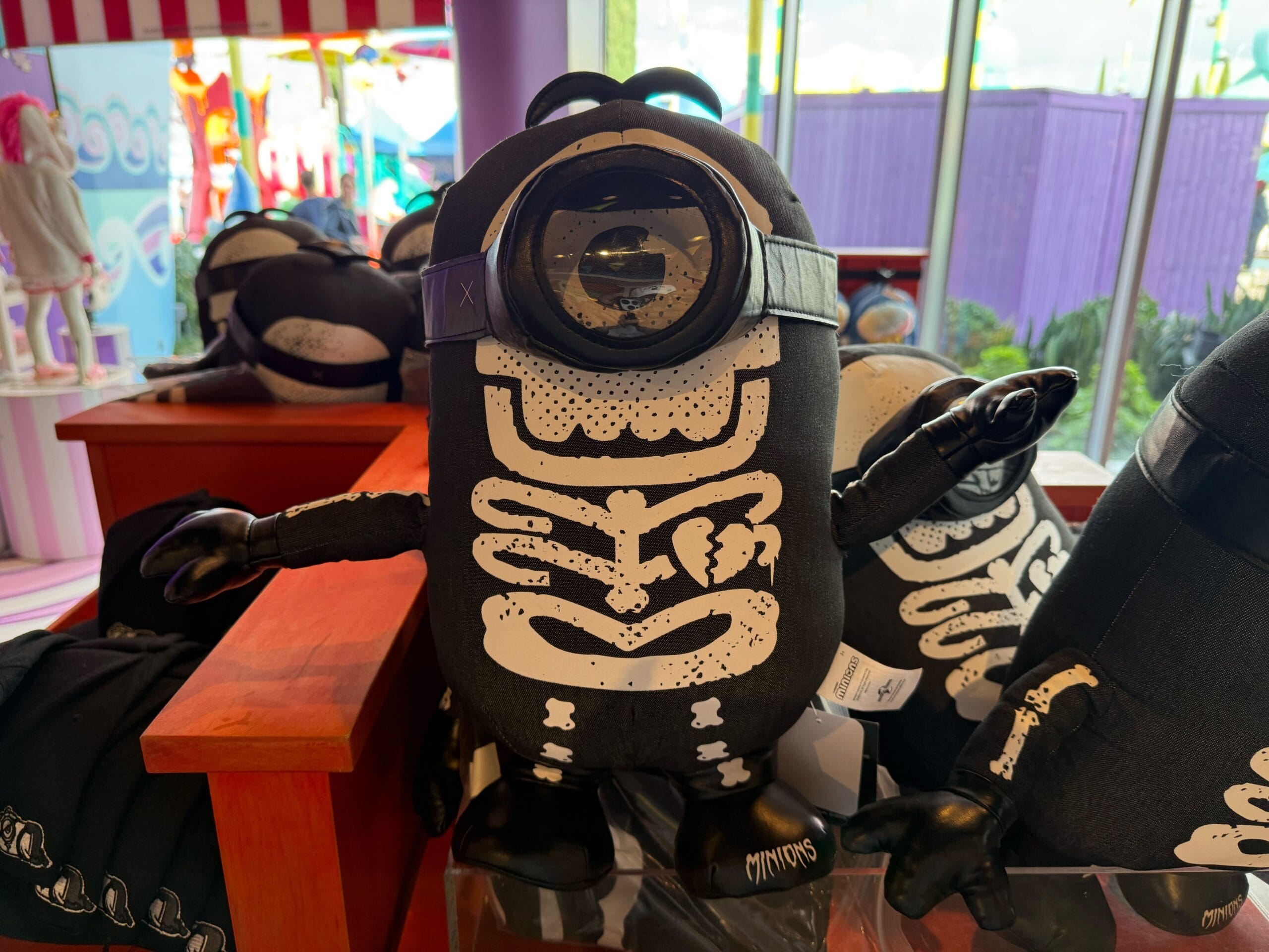An Emo Minion plush with a skeleton design sits on a shelf, not far from the unique castle silhouettes found at Disney parks worldwide.