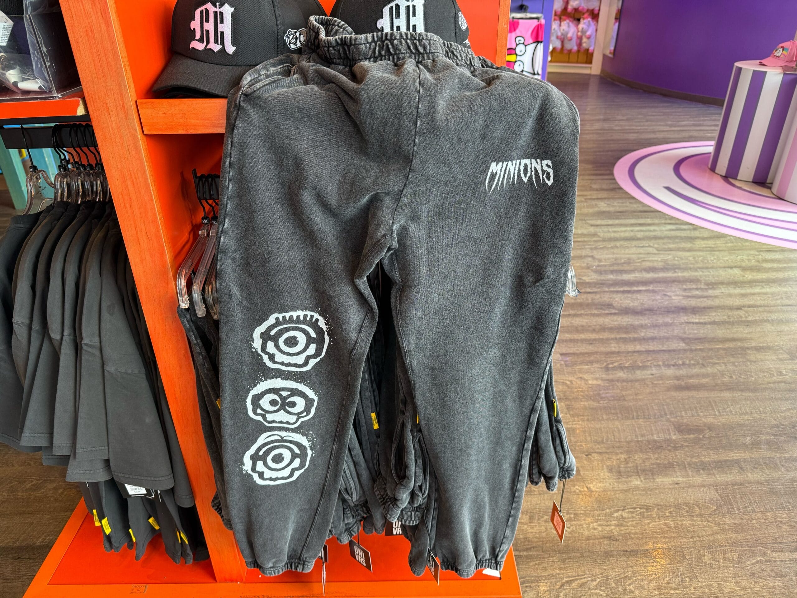 Black jogger pants with "Minions" text and eye graphics, similar to unique merch found at Disney Parks—but no castle pictured.