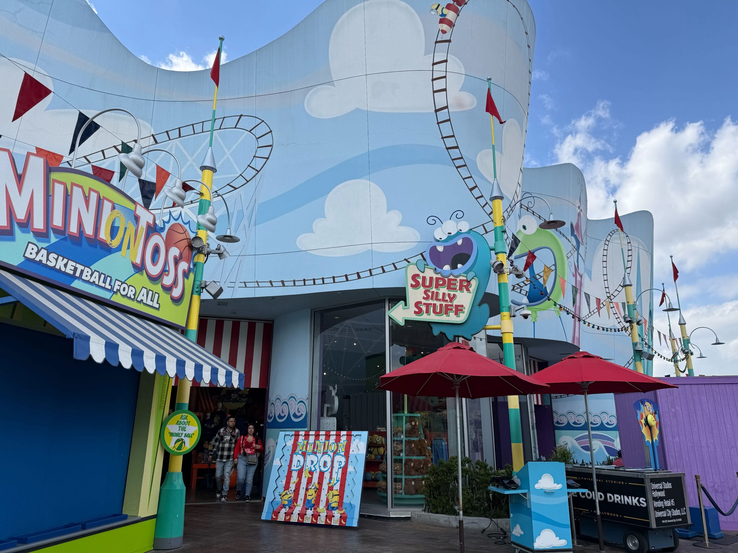 Vibrant amusement park zone with playful coaster art, game booths, and quirky character merchandise, distinct from Disney castles.
