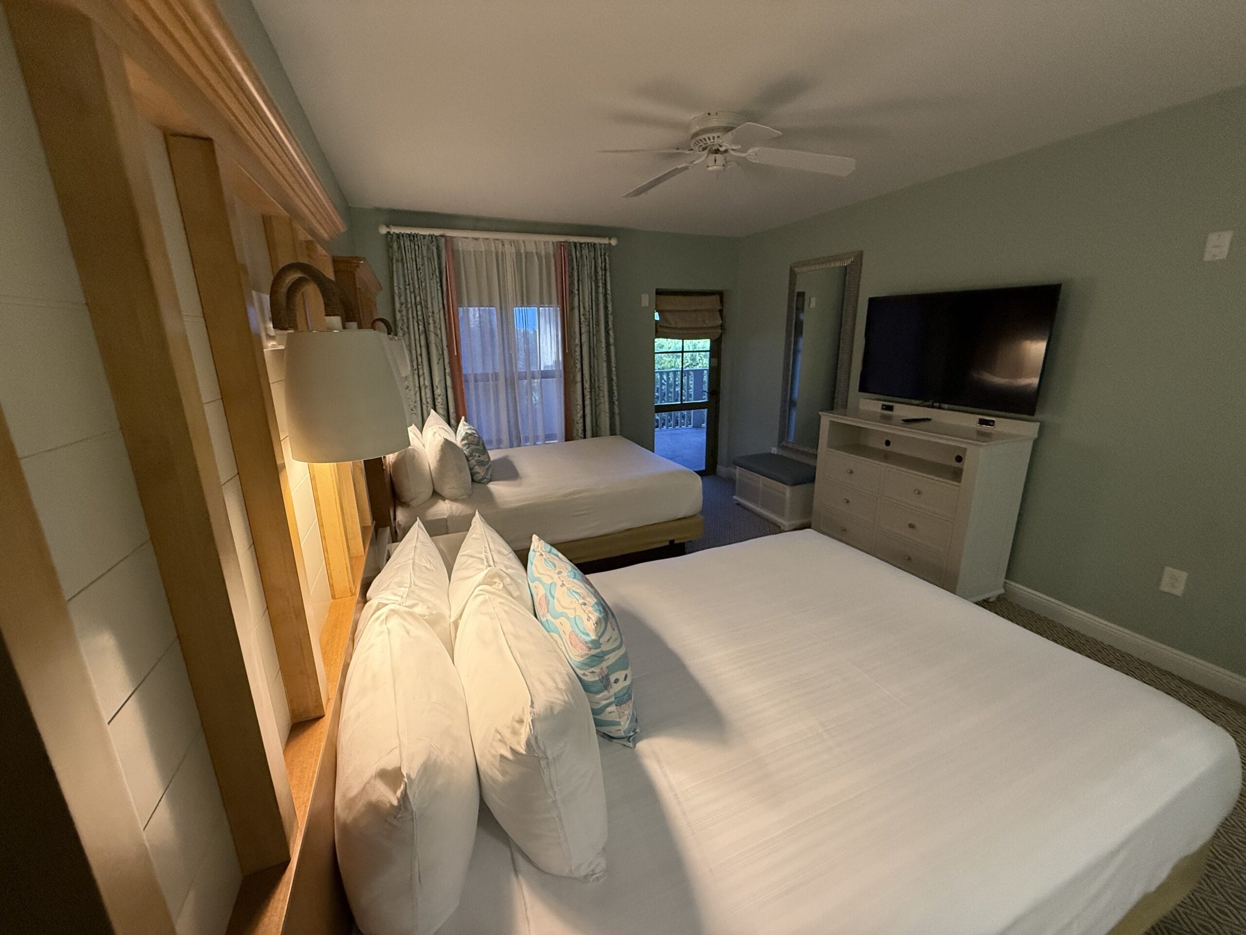 Hotel room at Disney's Vero Beach Resort with two double beds, TV, dresser, lamps, and window with closed curtains (no castle view).