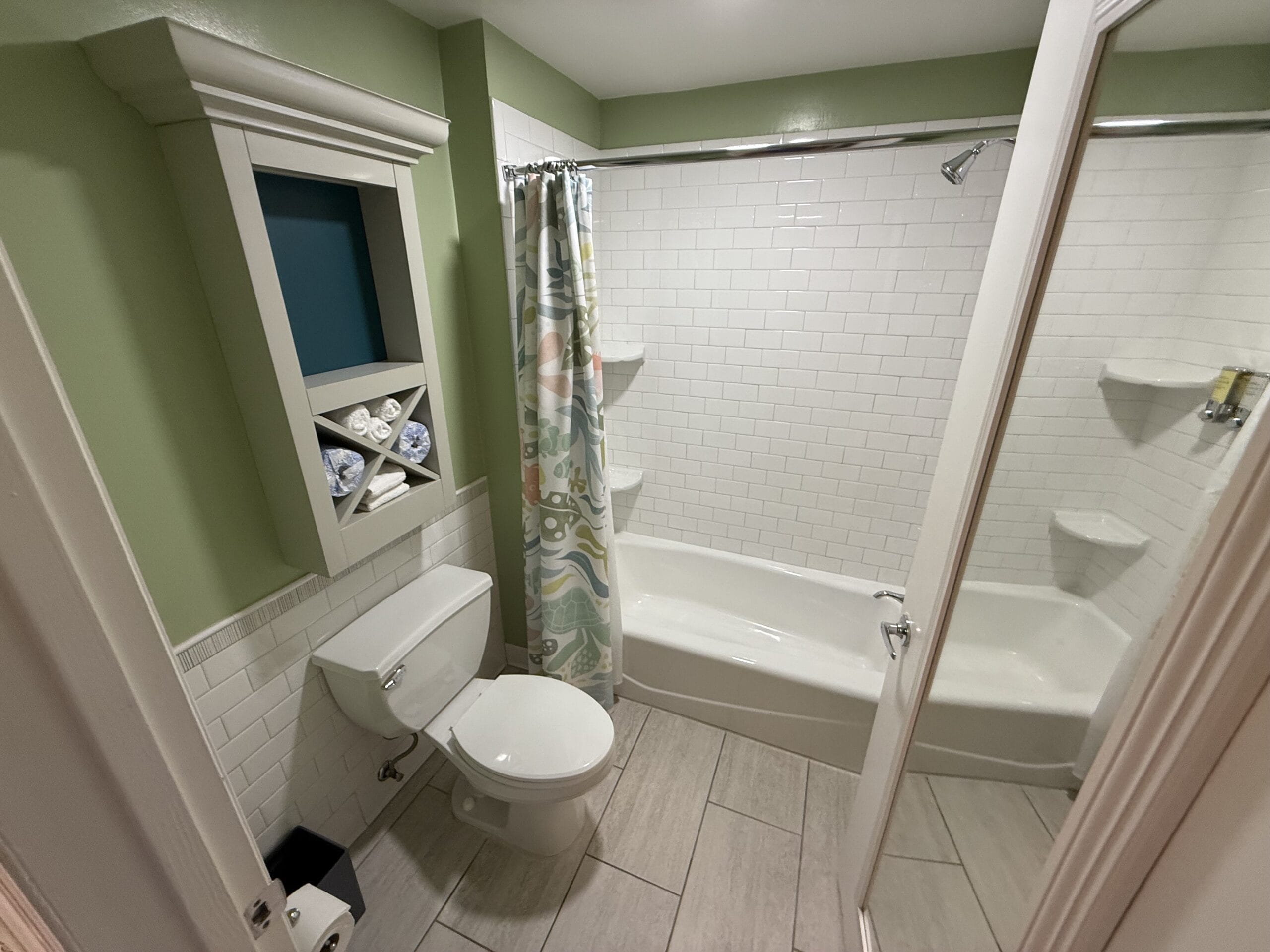 Bathroom in a 3 Bedroom Cottage at Disney's Vero Beach Resort with green walls, tub, and rolled towels—not a Disney castle scene.