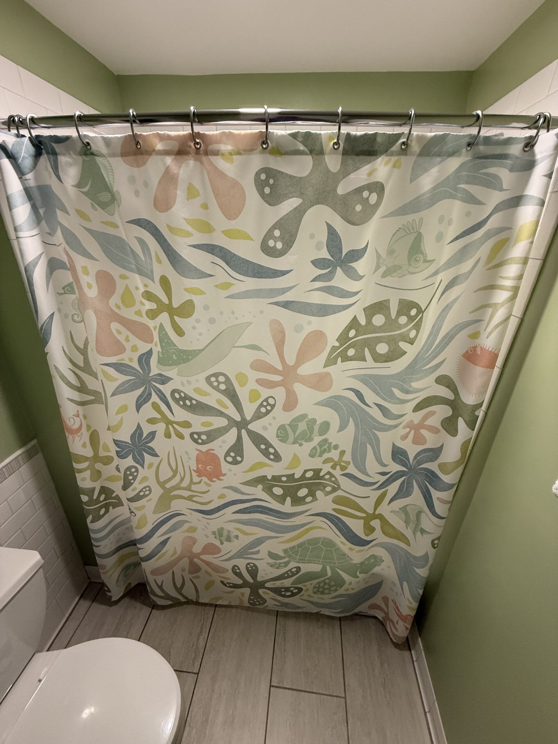 Vibrant, abstract-patterned shower curtain brightens a cozy bathroom at Disney’s Vero Beach Resort 3-Bedroom Cottage.