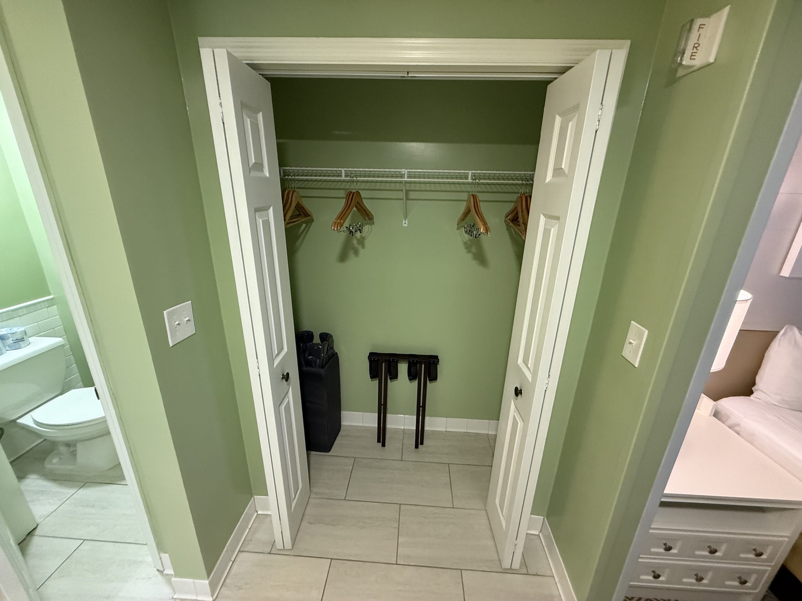 Open closet at Disney's Vero Beach Resort 3 Bedroom Cottage, hangers, luggage racks, ironing board; bath & bedroom visible. No castle here—unlike those iconic park views!