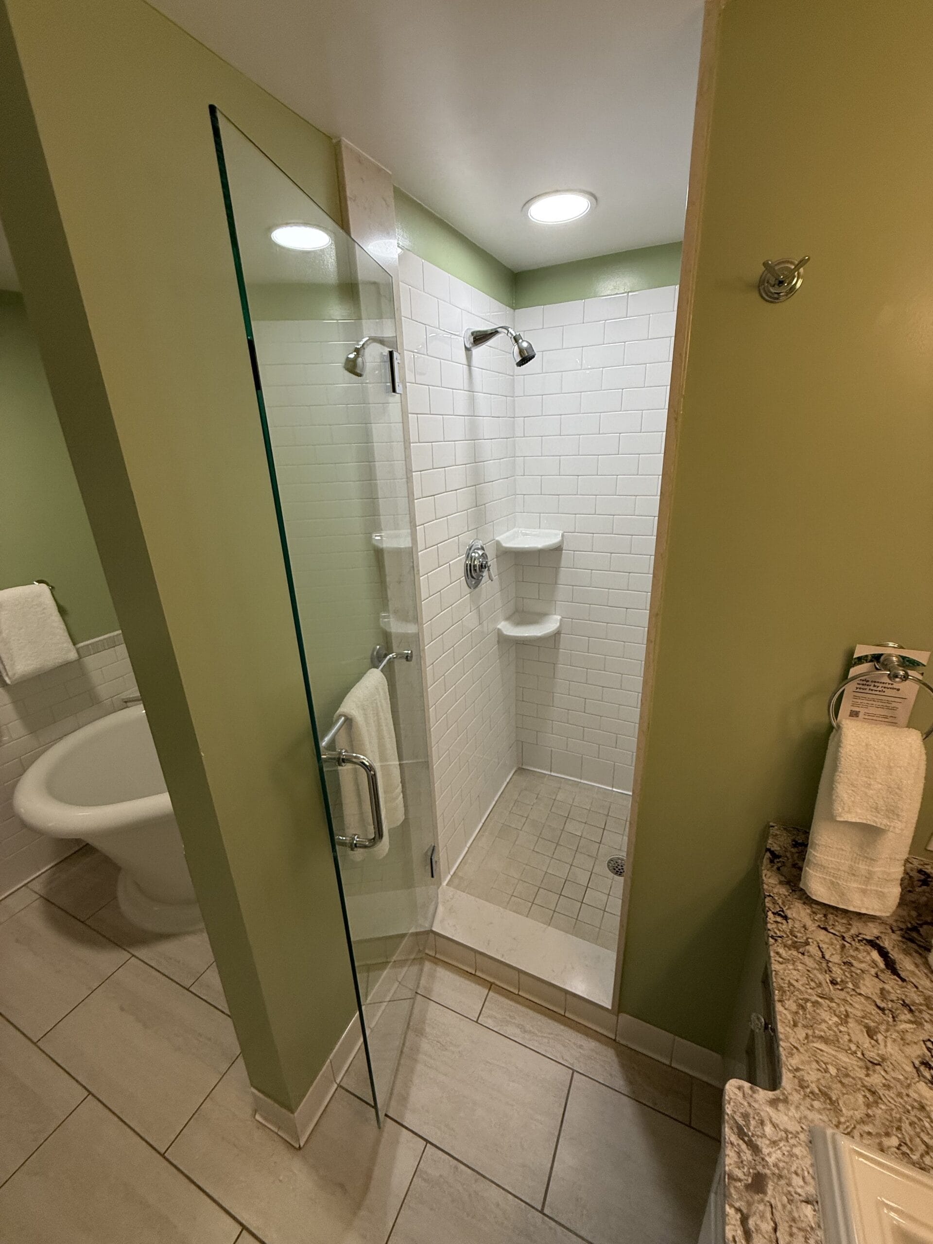 A small, white-tiled shower with a glass door in a 3 Bedroom Cottage at Disney's Vero Beach Resort, no castle like those in the parks.