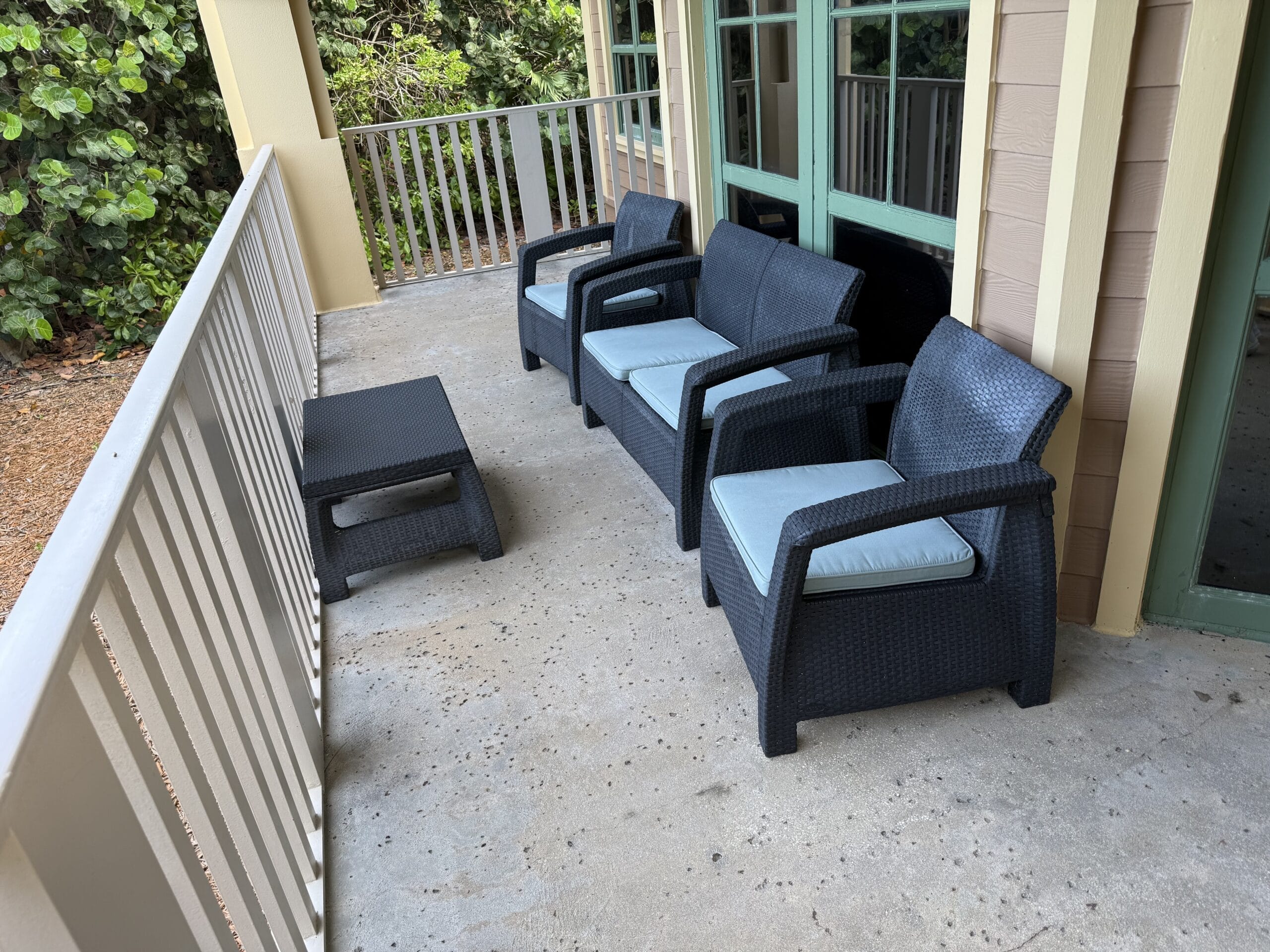 Three black patio chairs and a table on a porch at Disney’s Vero Beach Resort 3 Bedroom Cottage, with no castle view like at Disney parks.