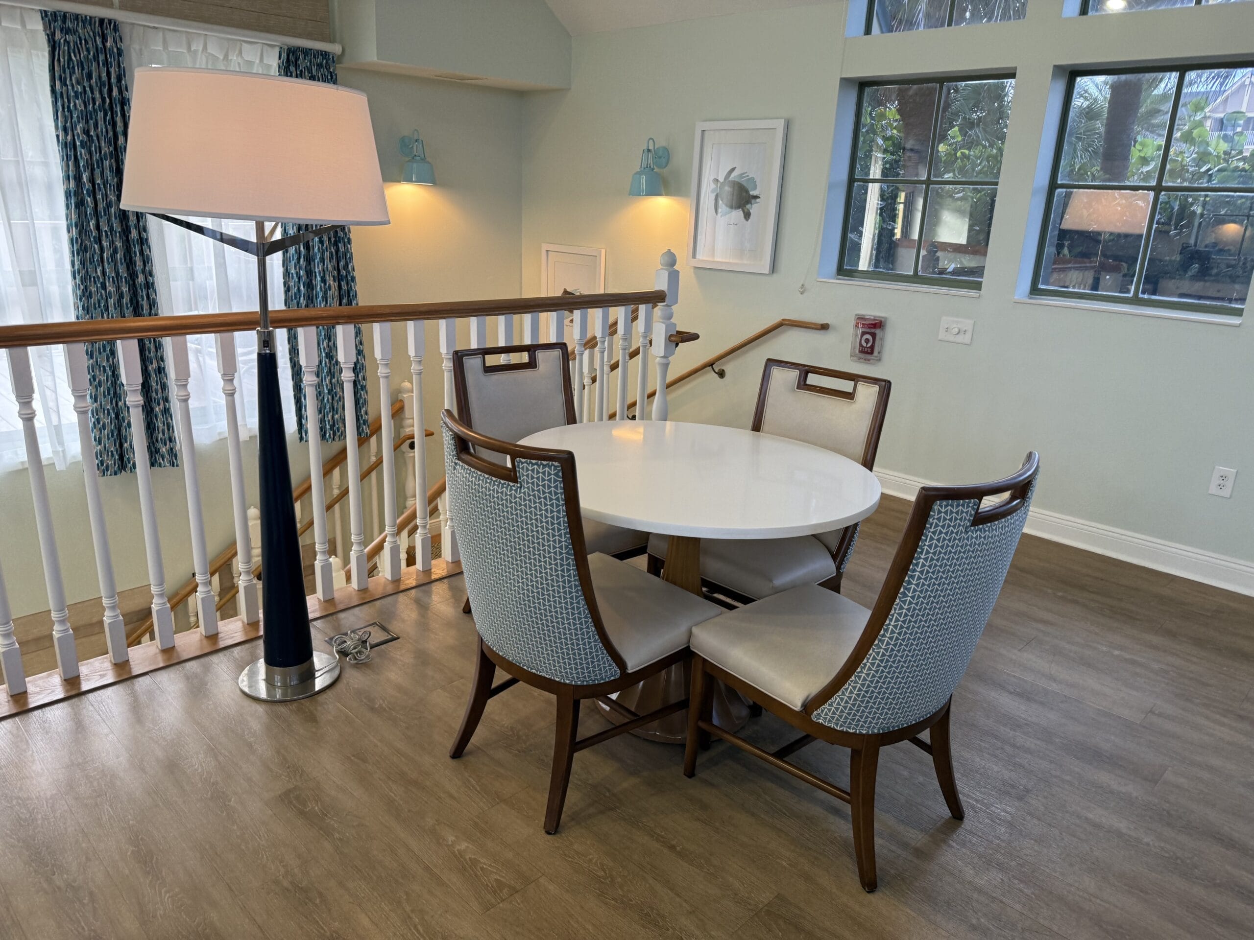 A round white table with four chairs and a lamp, reminiscent of Disney’s Vero Beach Resort 3 Bedroom Cottage, no park castle shown.