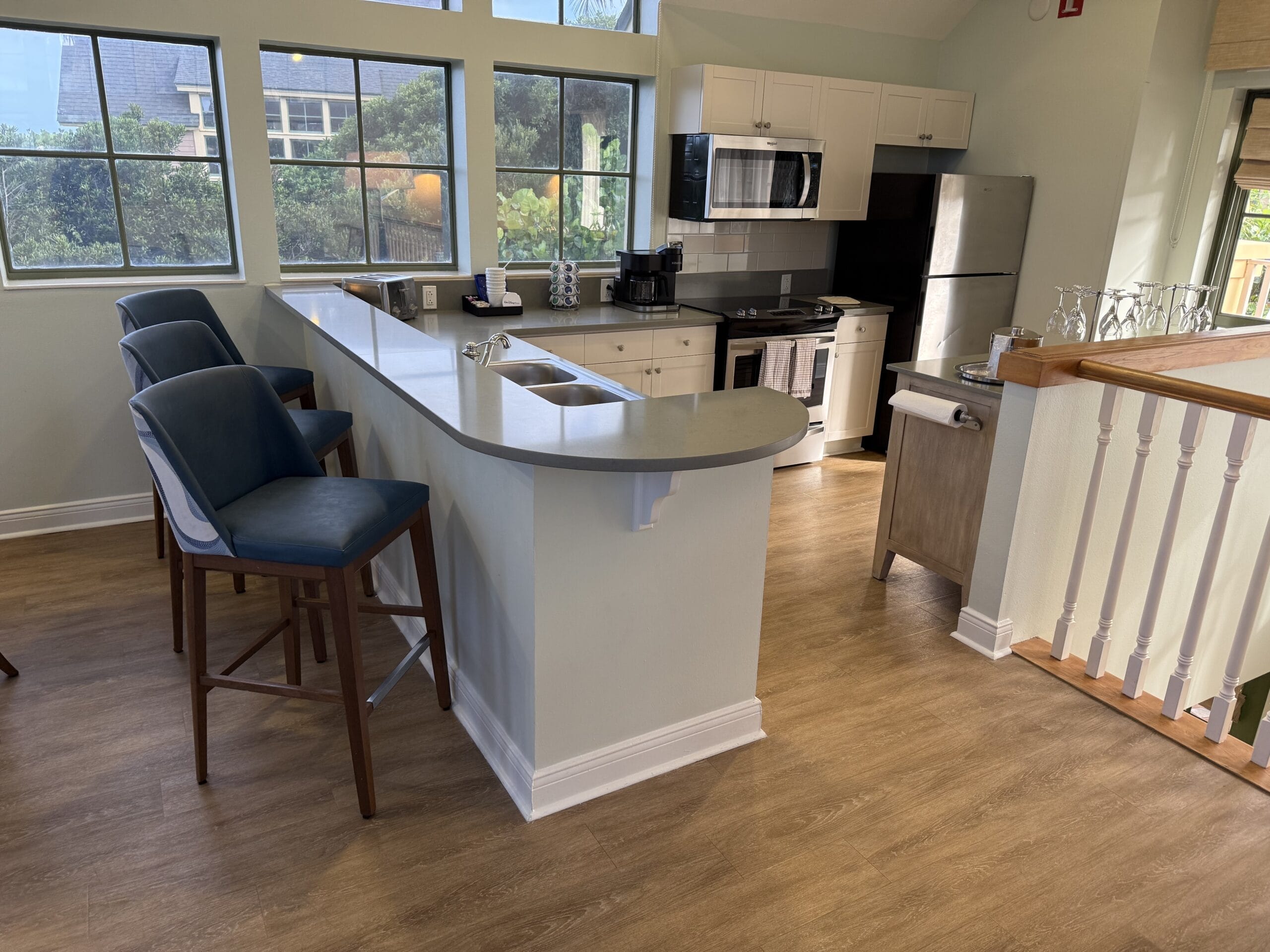 Modern kitchen at Disney’s Vero Beach Resort, curved counter, blue stools, large windows; no castle like Magic Kingdom’s nearby.