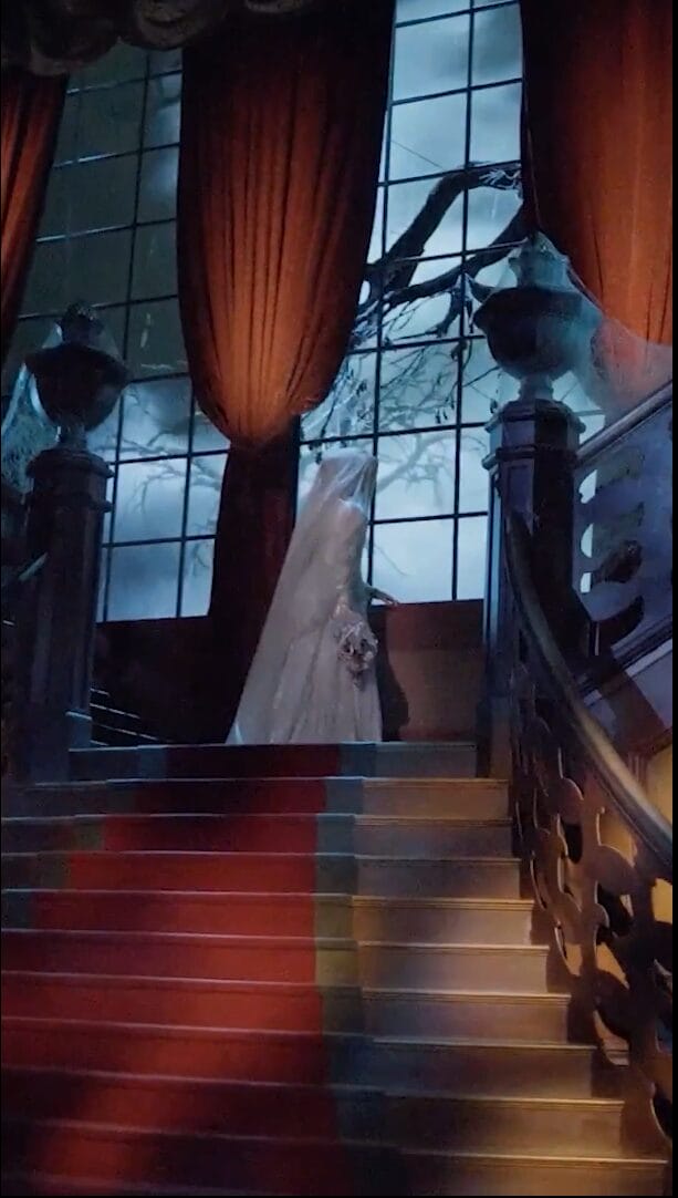 Animatronic of the Bride as she stares out a window at a stormy scene atop a staircase in Phantom Manor in Disneyland Paris.