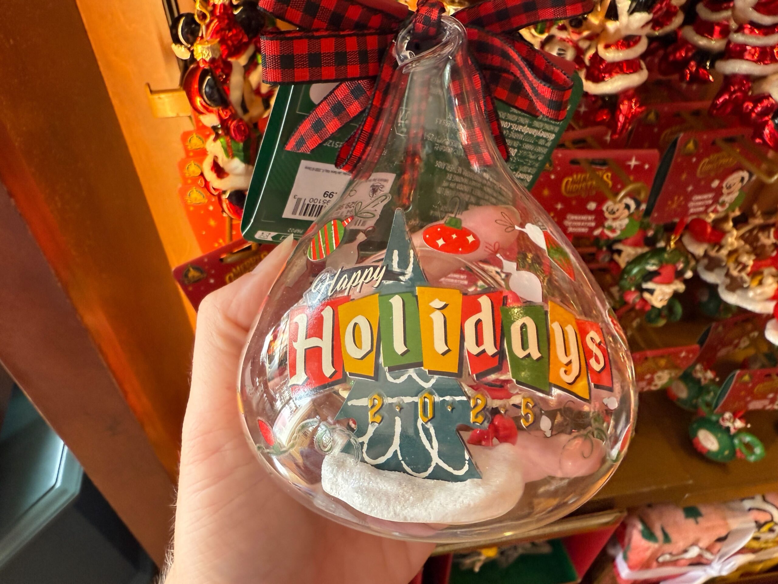 Hand holding a glass ornament shaped like a Hershey’s Kiss, perfect Christmas merchandise for Walt Disney World fans.