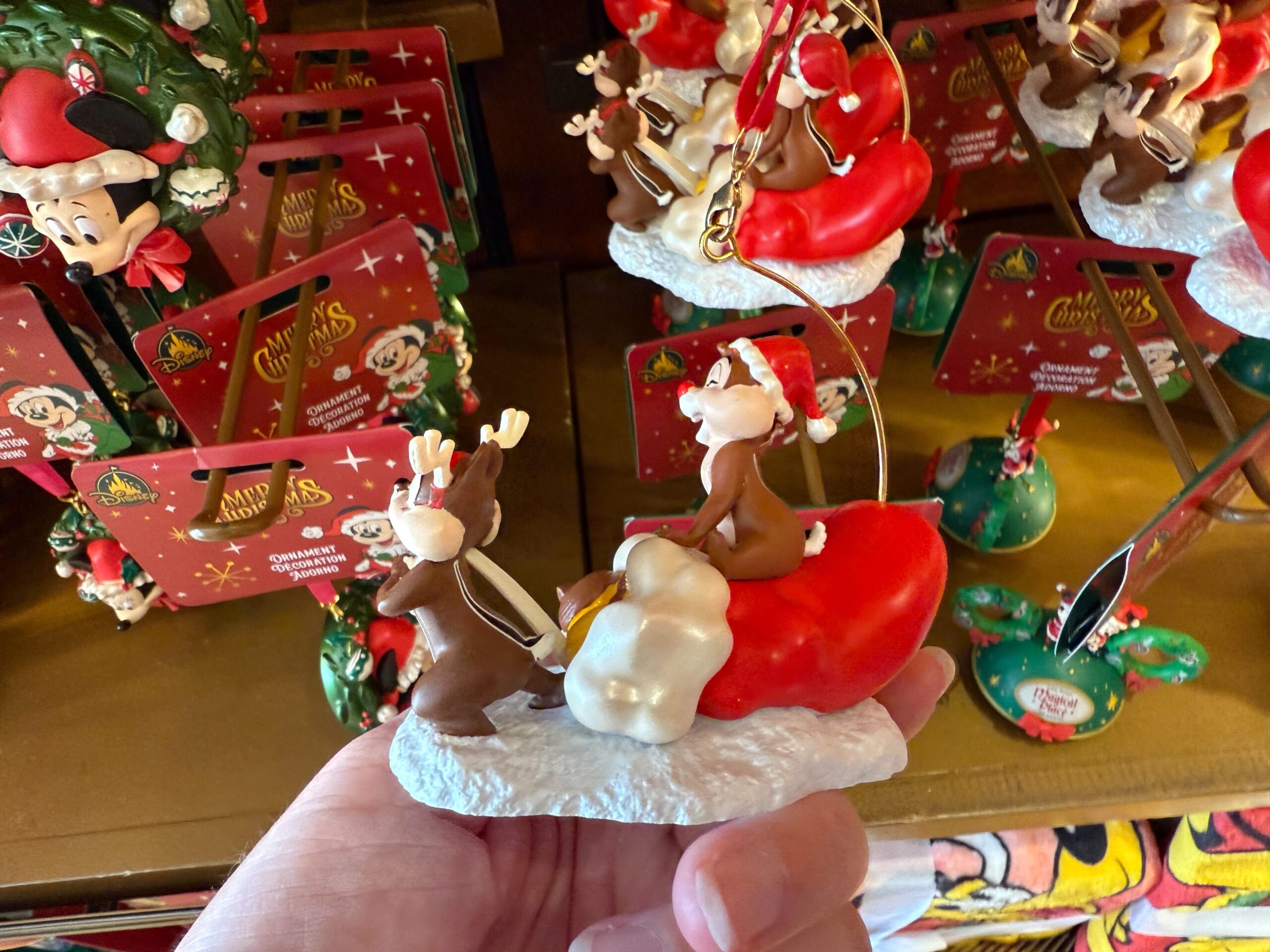 Hand holds a 2025 Christmas ornament of two reindeer in Santa hats on a sleigh, perfect for Walt Disney World fans.