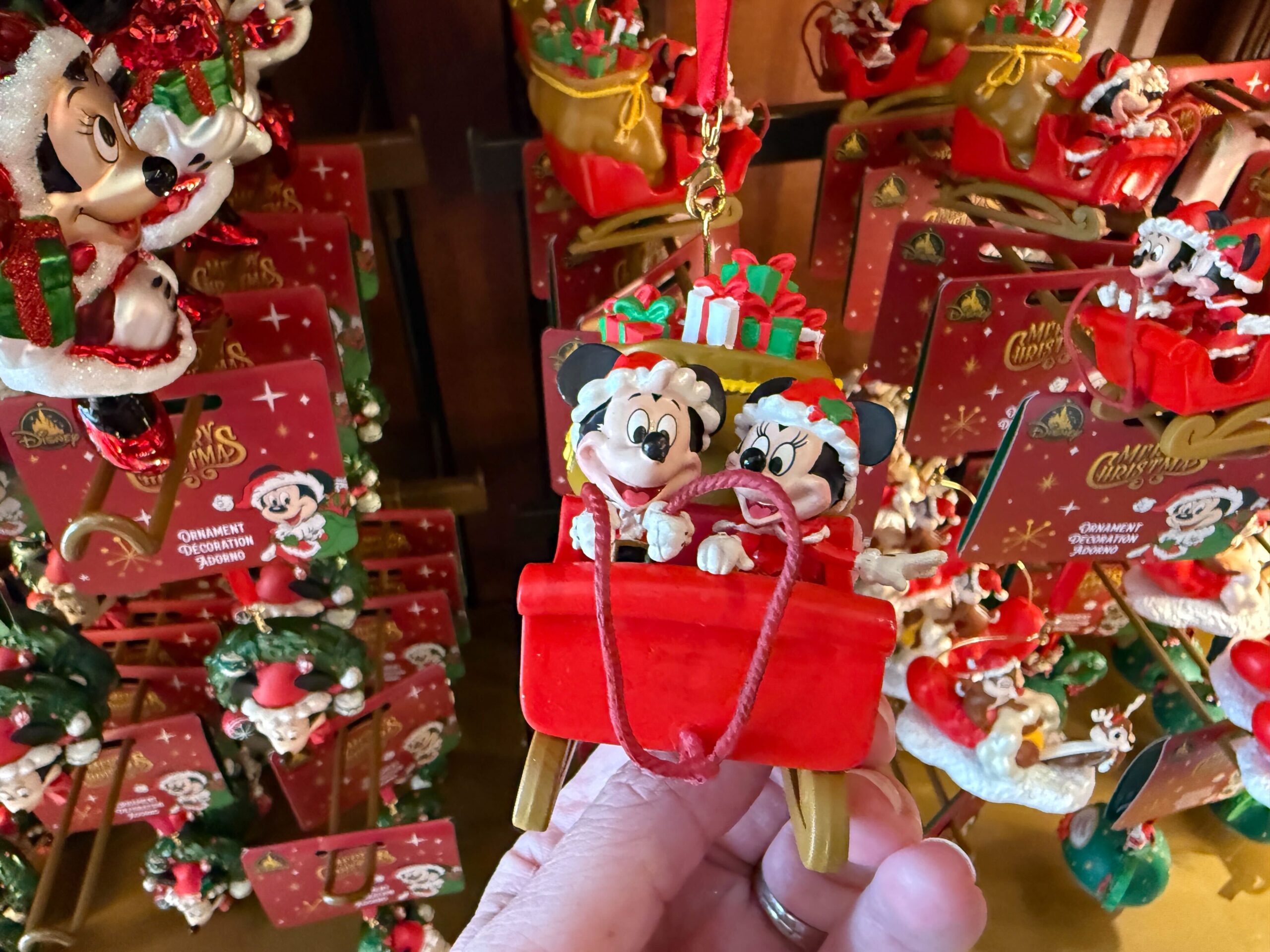 Hand holding a Mickey and Minnie Mouse Christmas ornament, part of the Disney World Christmas merchandise collection.