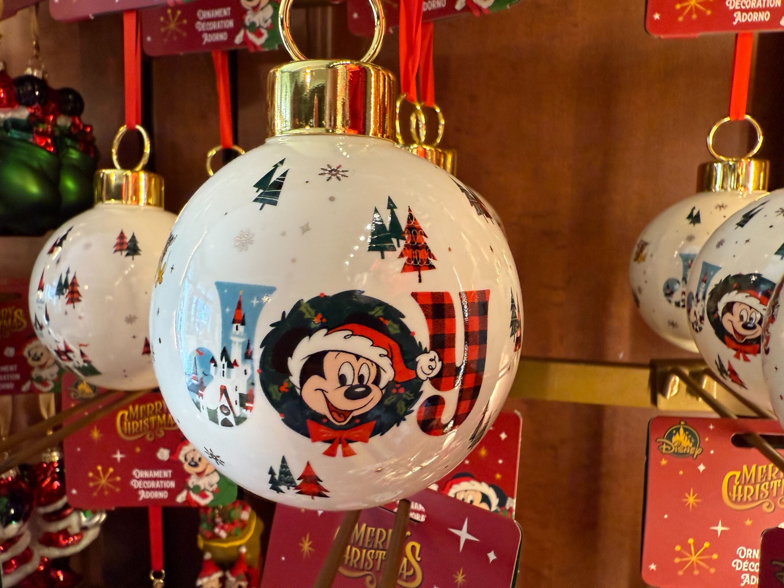 A white Walt Disney World ornament features Mickey Mouse in a Santa hat, surrounded by festive 2025 decorations.