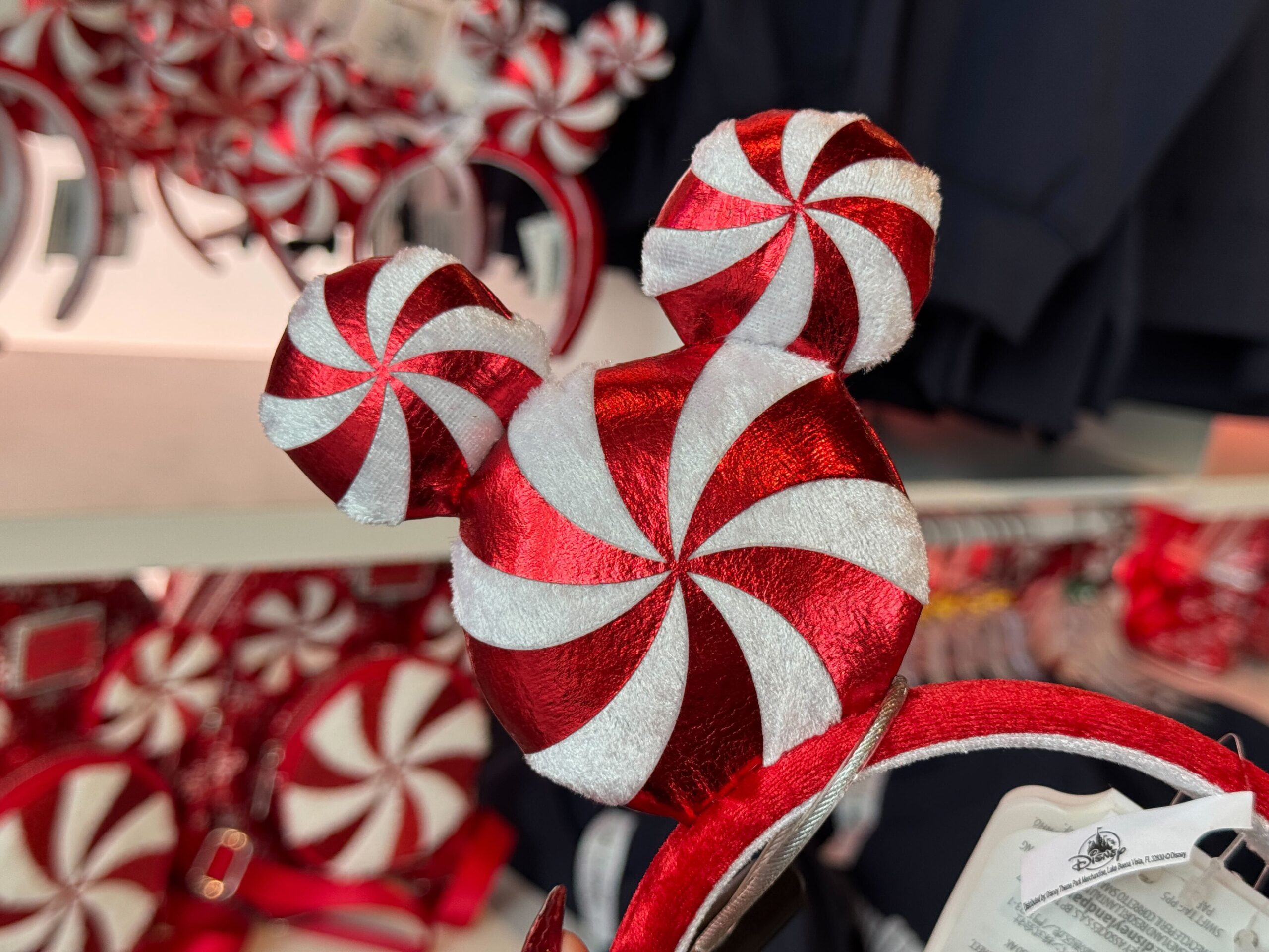 Red and white peppermint Mickey Mouse ear headband, festive 2025 Christmas merchandise at Walt Disney World store.