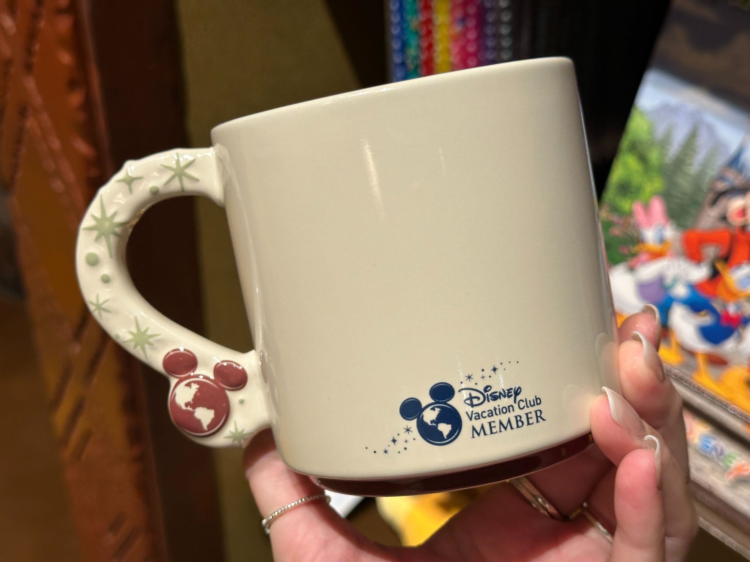 A hand displays a DVC mug featuring Mickey icons on the handle at Disney’s Animal Kingdom Villas, with no castle in view.