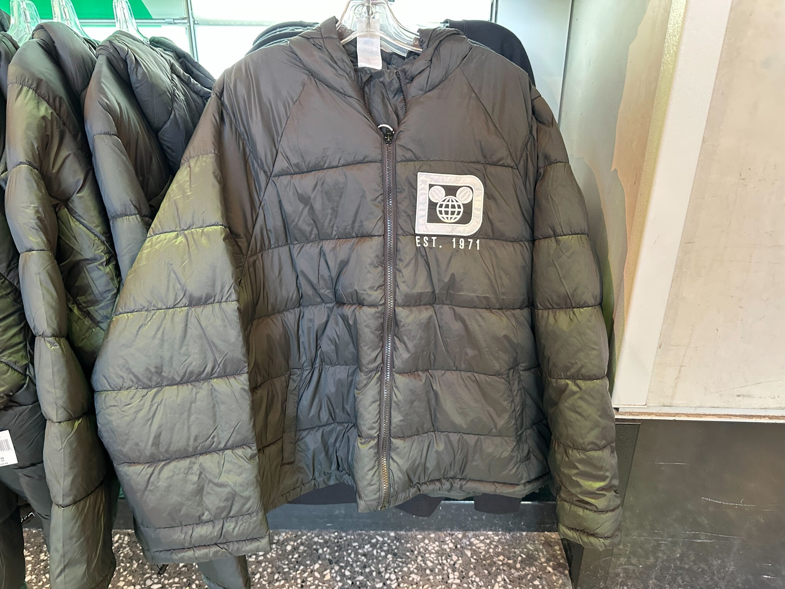 Black puffer jacket from Walt Disney World with bear face patch, globe, and "EST. 1971"—uniquely tied to WDW, not Disneyland.