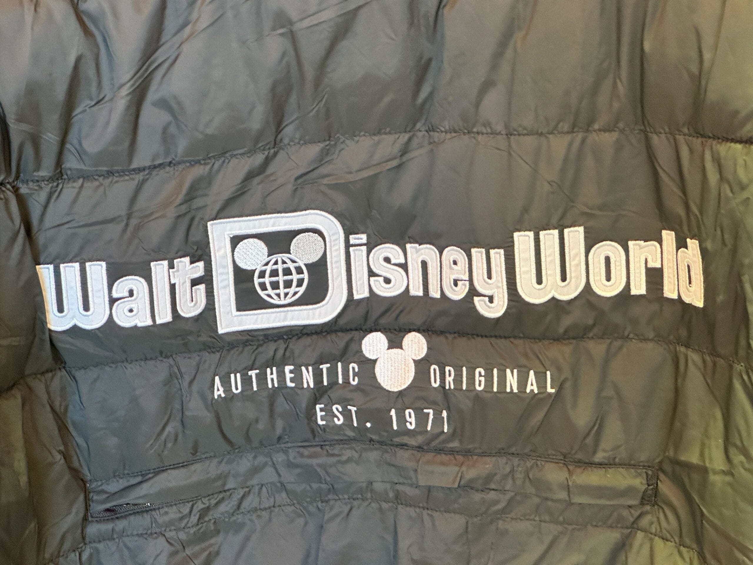 Close-up of a black Authentic Original Jackets coat featuring "Walt Disney World" in white, referencing the Florida park's iconic branding.