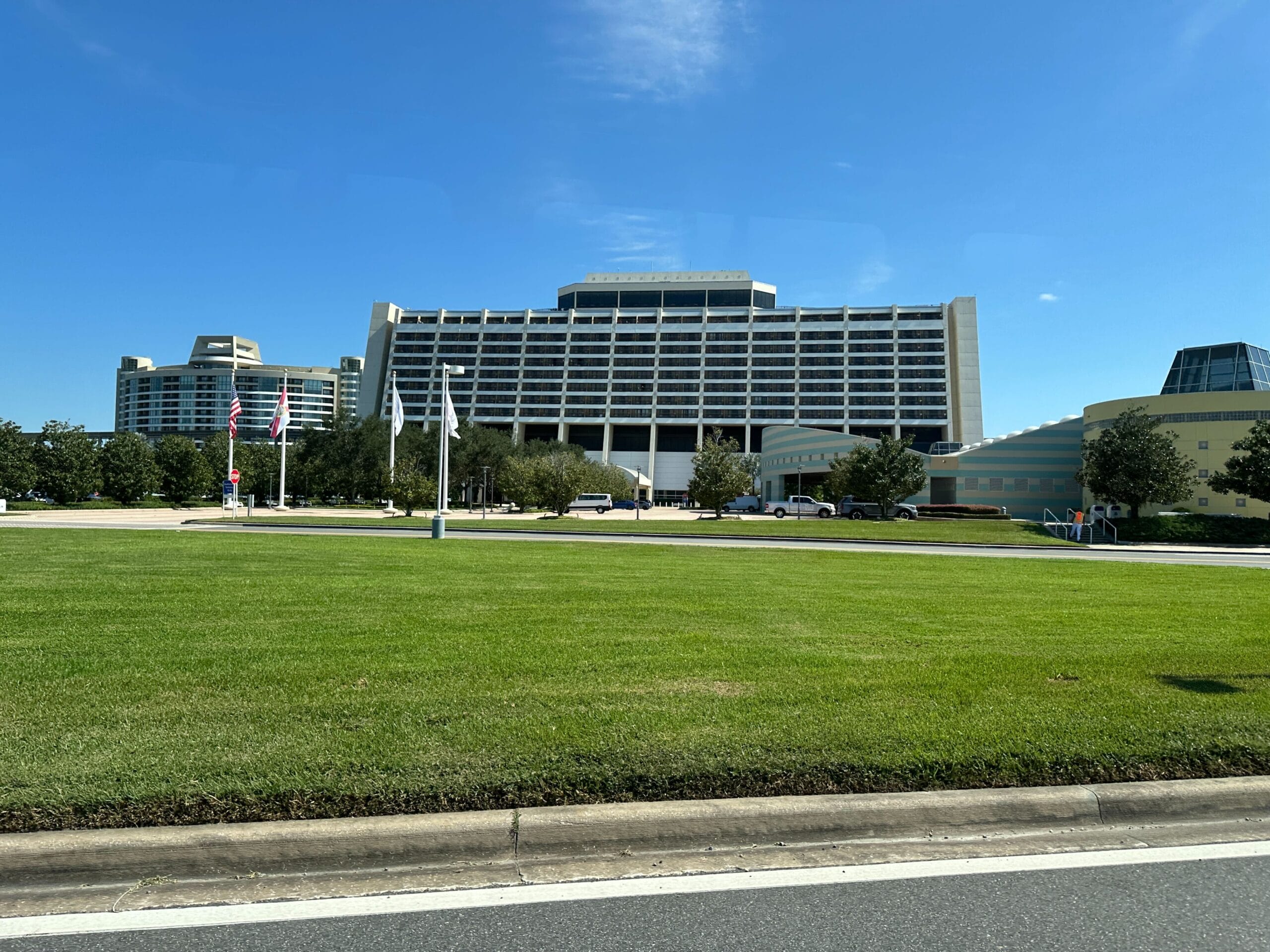 Large A-frame Contemporary Resort at Walt Disney World, American flags flying, lush green lawn, clear blue sky above.