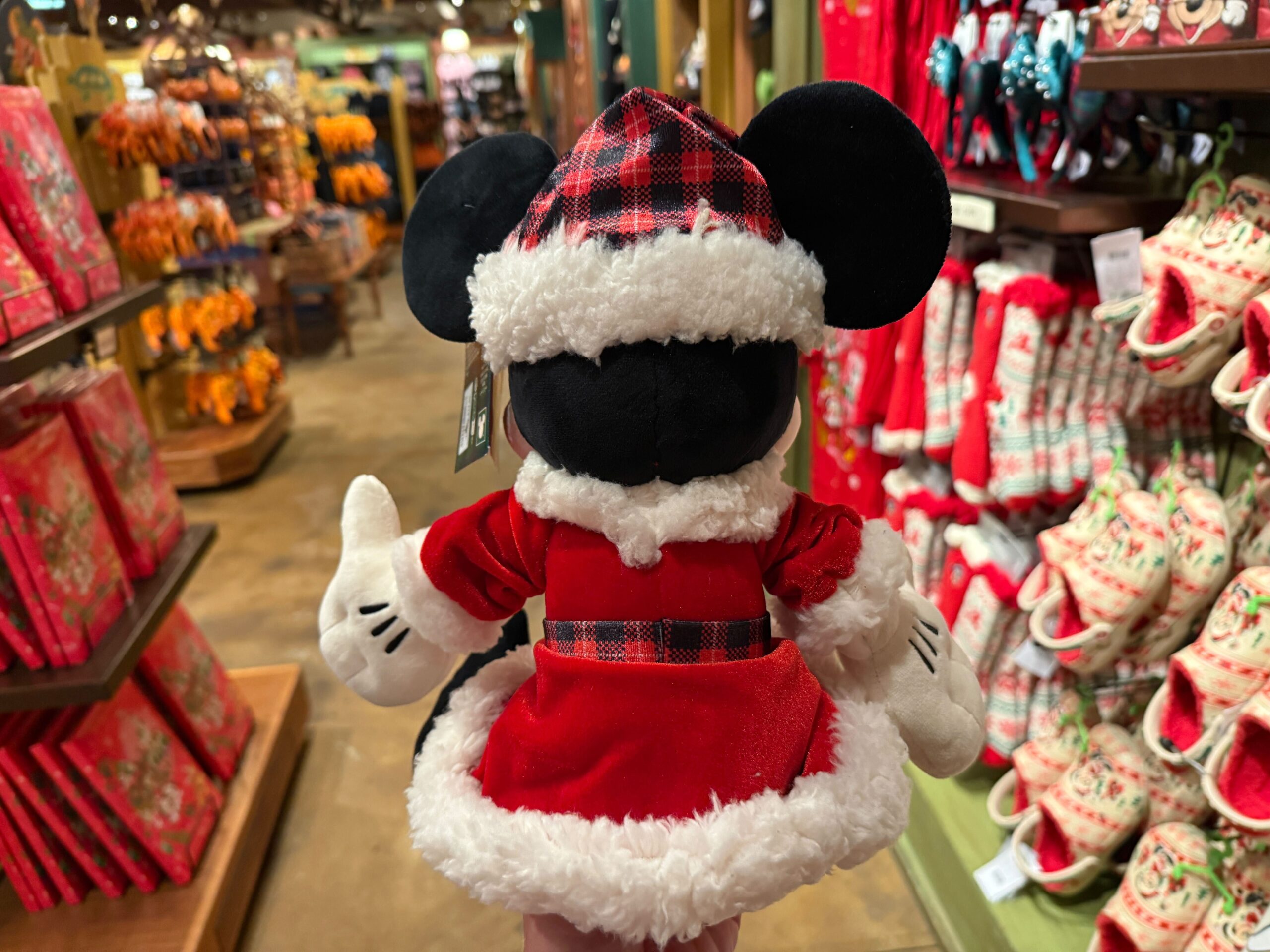A plush Minnie Mouse in a red holiday outfit shines among Walt Disney World Christmas merchandise for 2025.