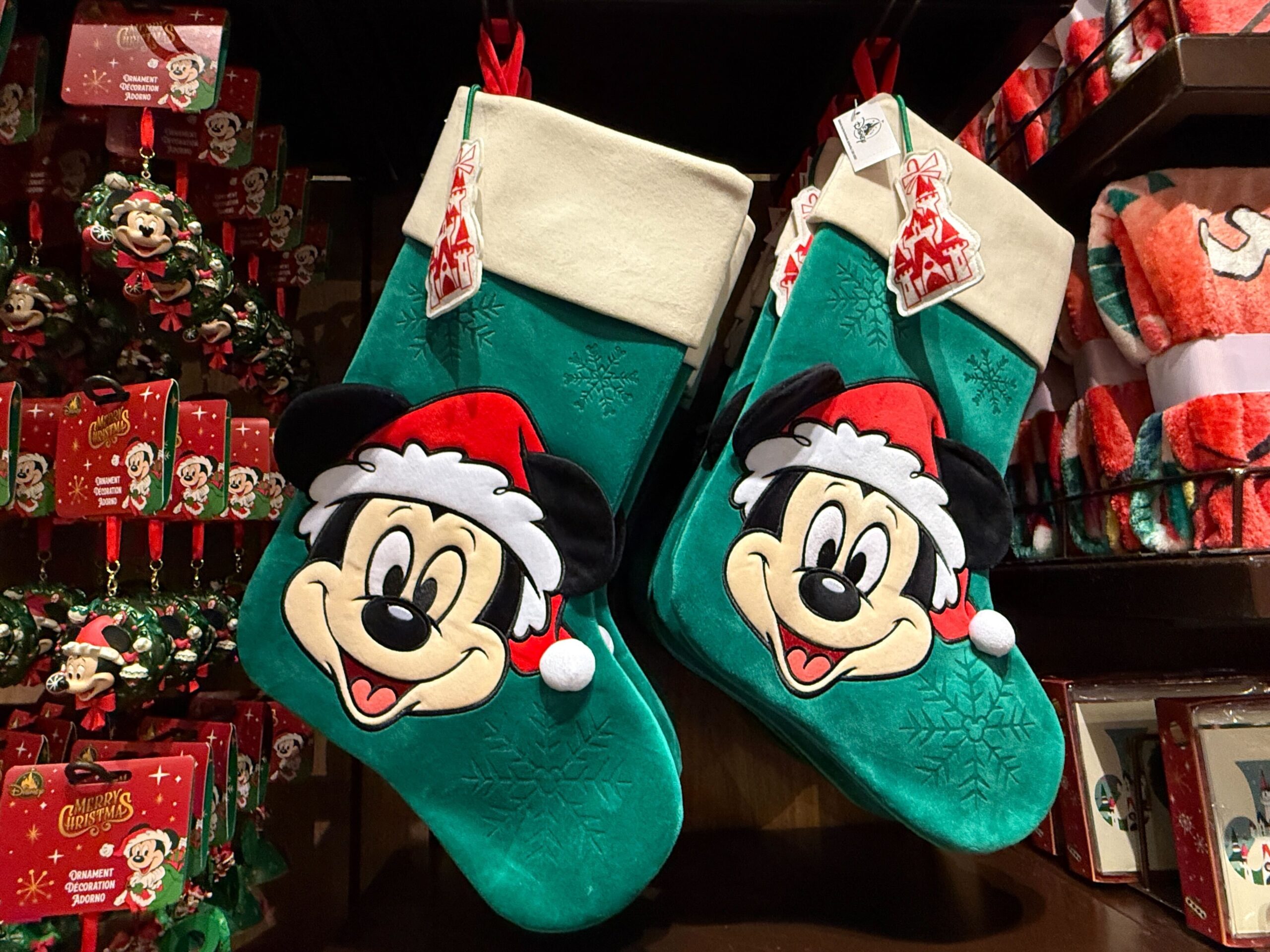 Two teal Christmas stockings featuring Santa hat Mickey Mouse faces are on display as Walt Disney World Christmas merchandise.