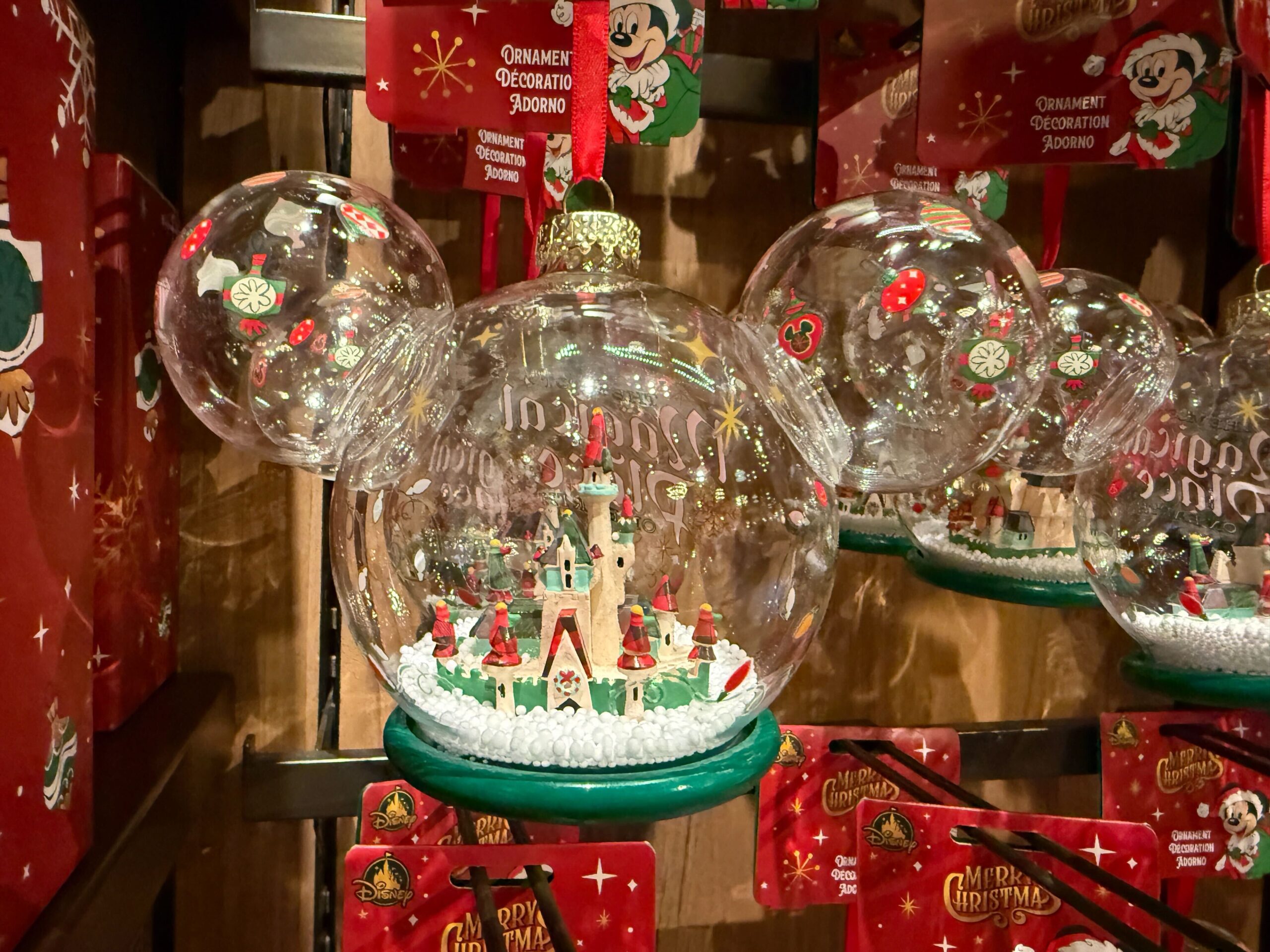 Clear Mickey Mouse-shaped ornament with a miniature Christmas castle scene, part of 2025 Walt Disney World Christmas merchandise.