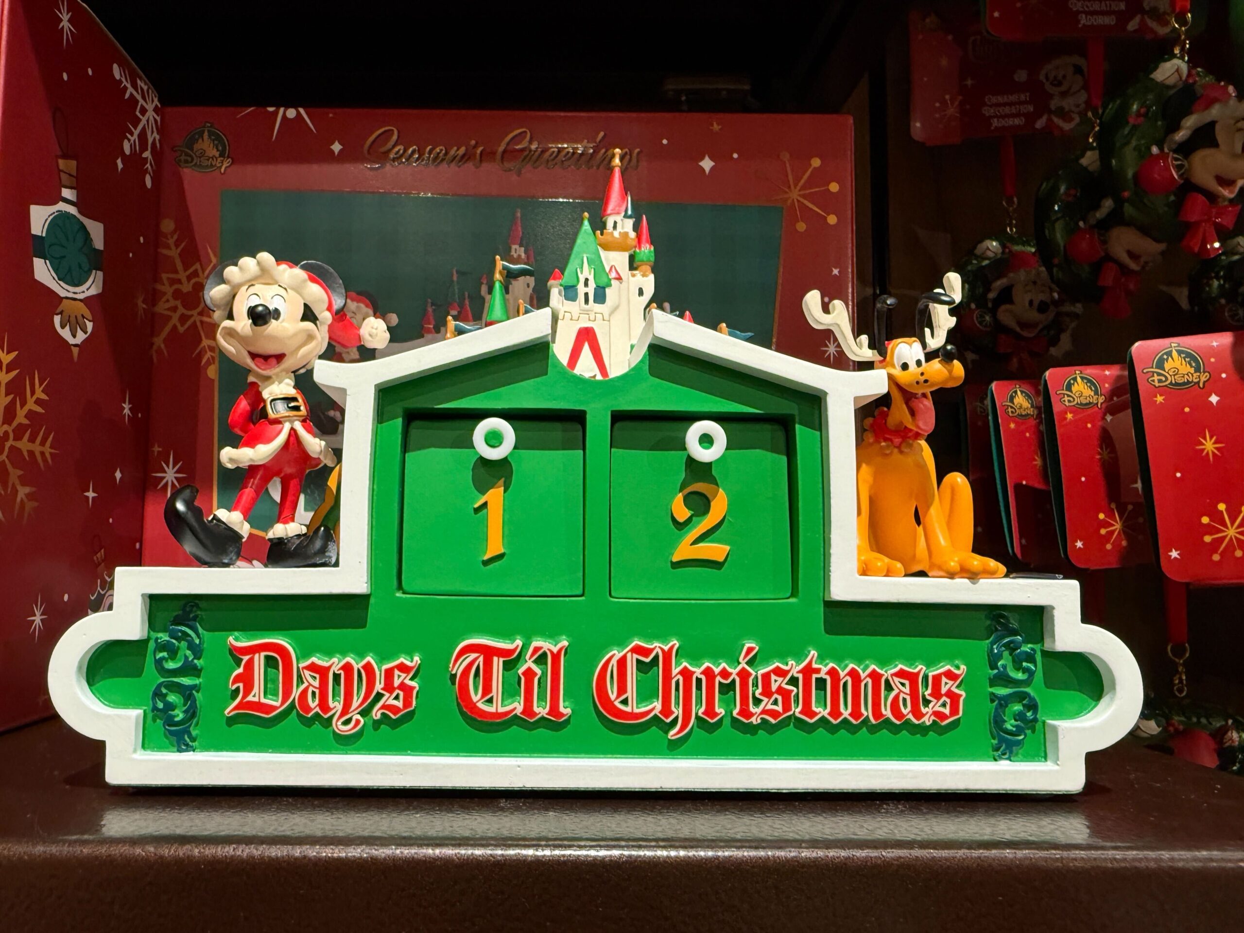A countdown sign with Mickey, Pluto, and a castle at Walt Disney World shows 12 days until Christmas in festive colors.