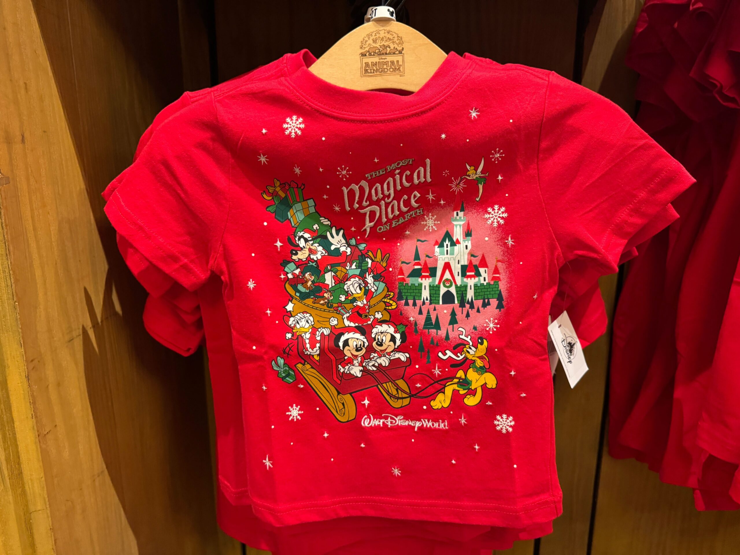 Red Walt Disney World t-shirt featuring Mickey, Minnie, and friends in a sleigh with a castle and snowflakes—perfect Christmas merchandise.