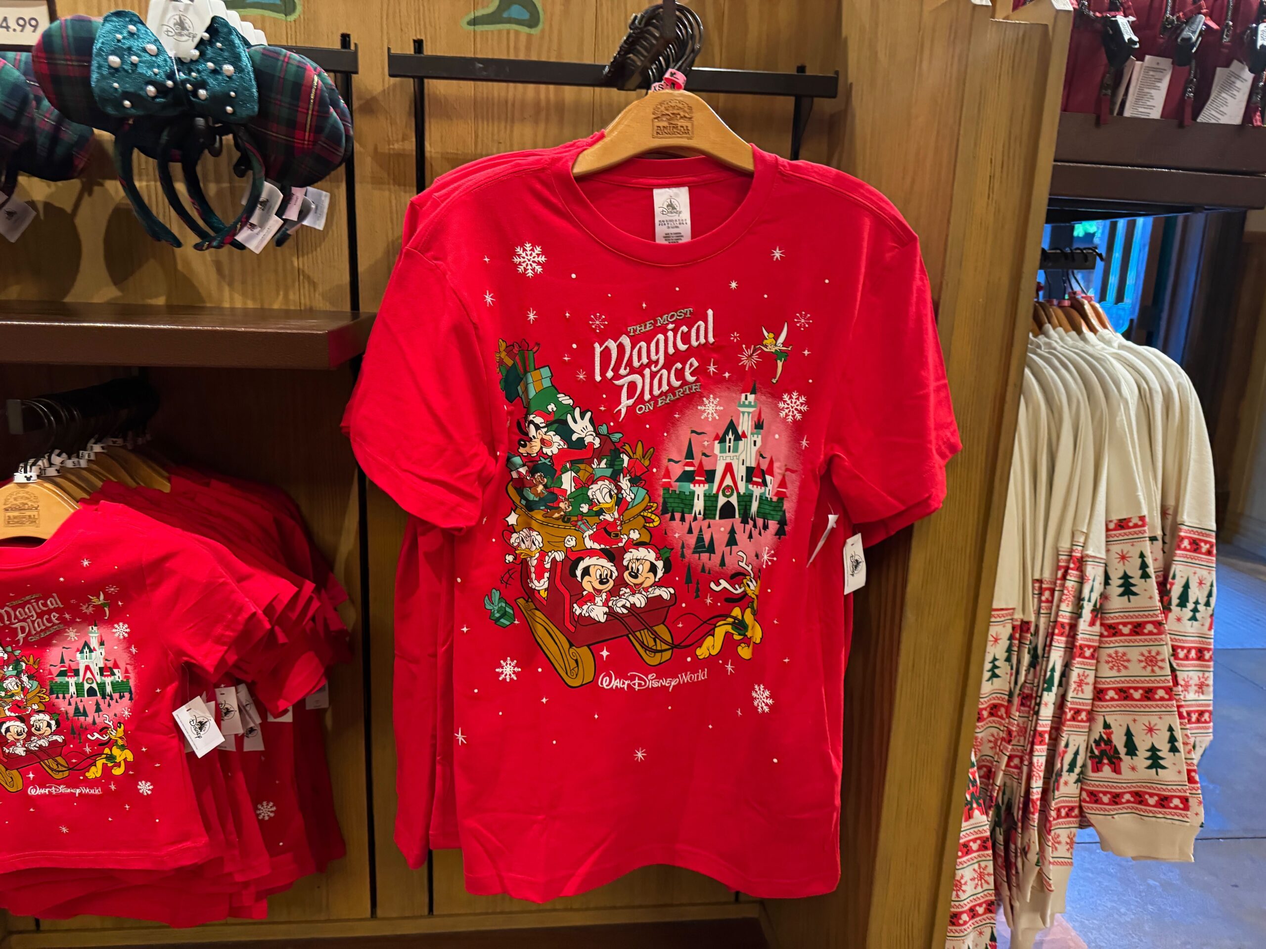 Red Walt Disney World Christmas merchandise t-shirt featuring Mickey, Minnie, friends in a sleigh, and “Magical Place” text.